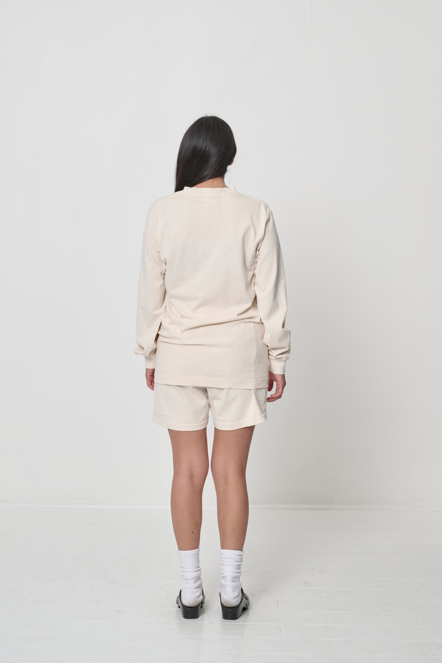 Full length back view of a person wearing a Scour Long Sleeve Trash Tee, with matching Everyday Shorts.