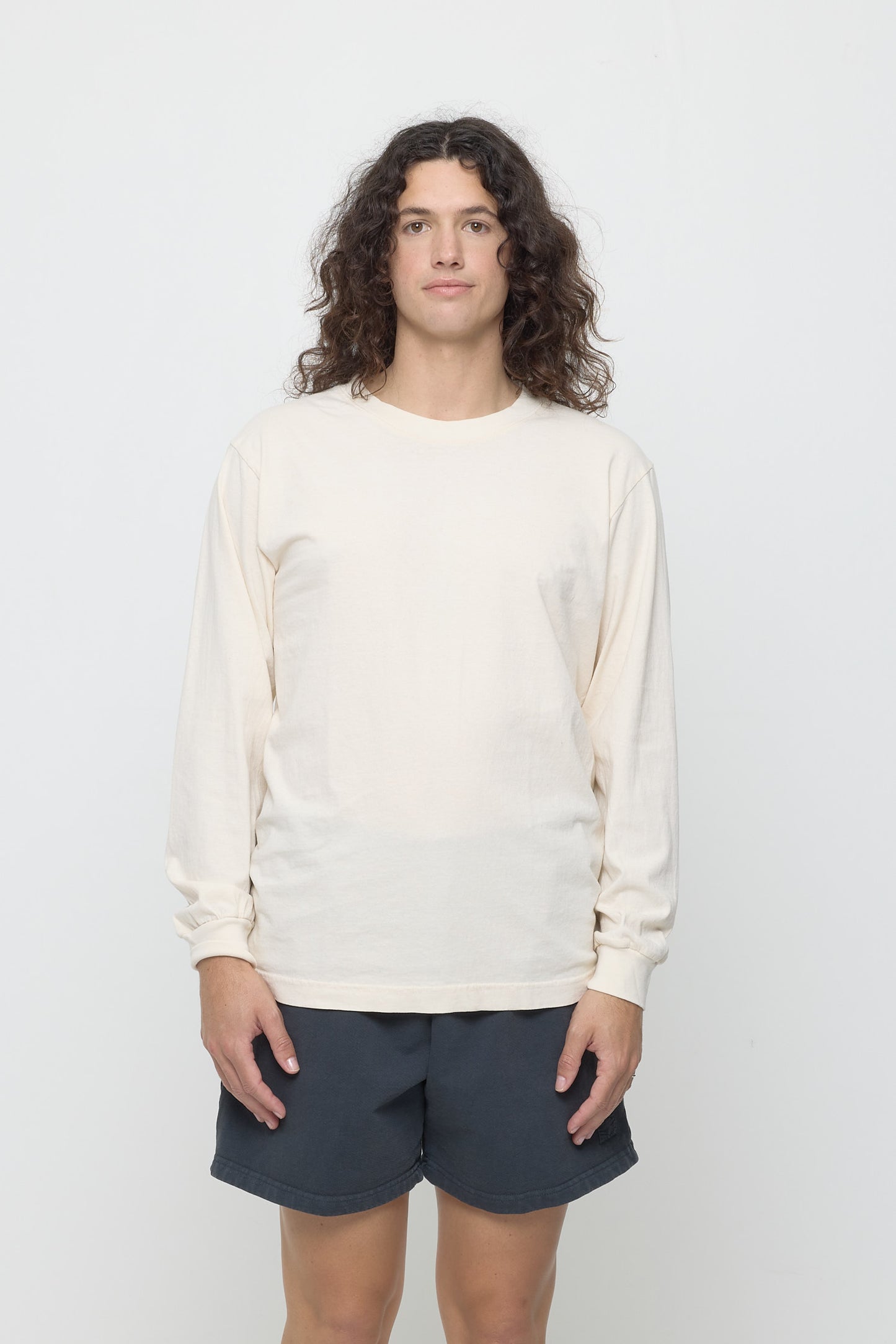 Closeup of a 6' person wearing a Slate Long Sleeve Trash Tee in size M. Shirt hem hits just below the hip.