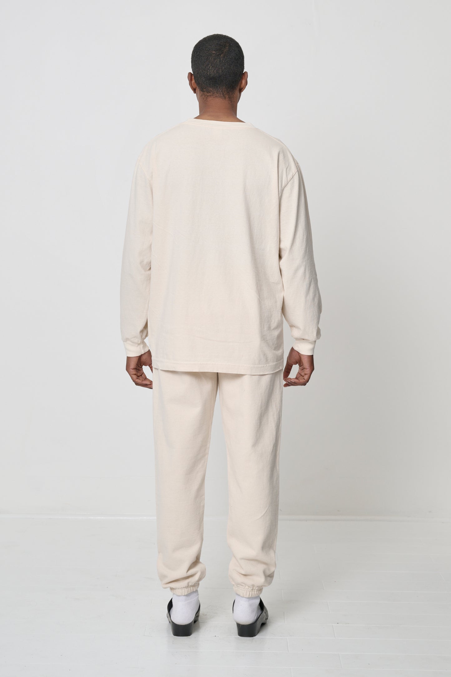 Full length back view of a person wearing a Scour Long Sleeve Trash Tee, with matching Trash Sweatpants.