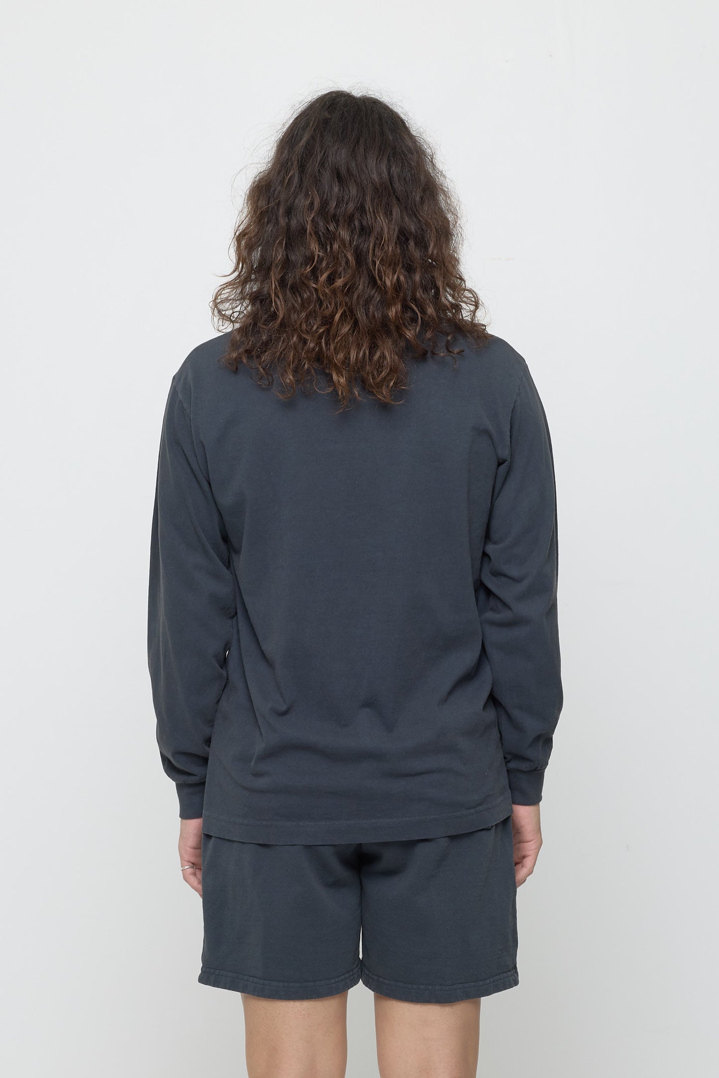 Closeup back view of a person wearing a Slate Long Sleeve Trash Tee, showing fabric drape and relaxed fit throughout.