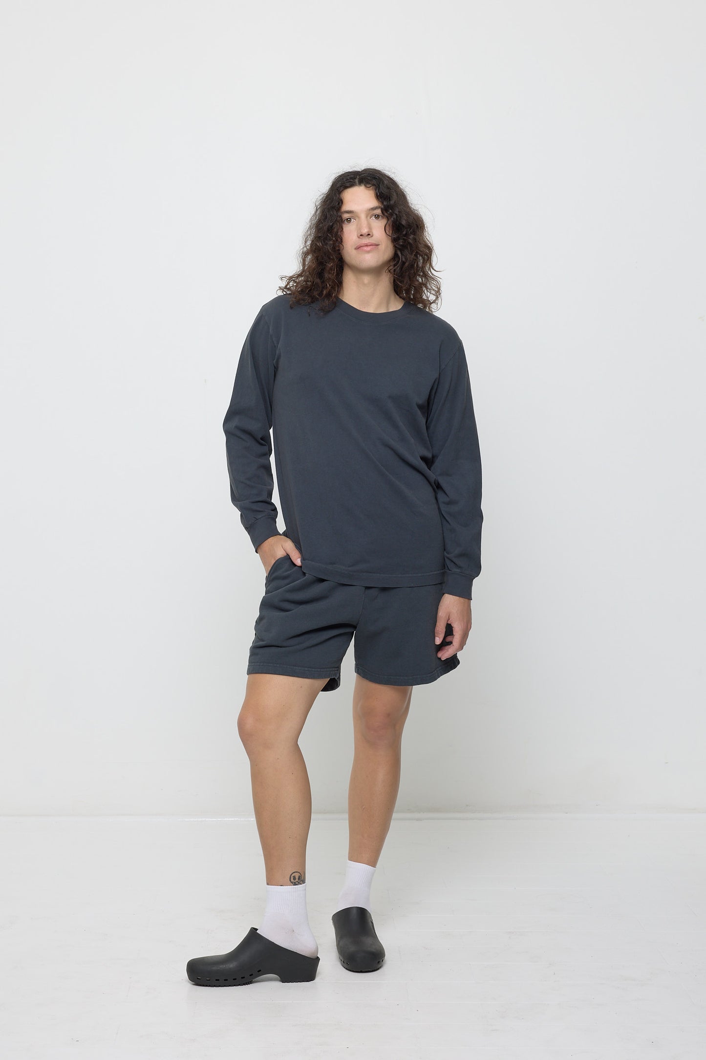 Full length of a person wearing a Slate Long Sleeve Trash Tee, with one hand in their Everyday Shorts pocket.