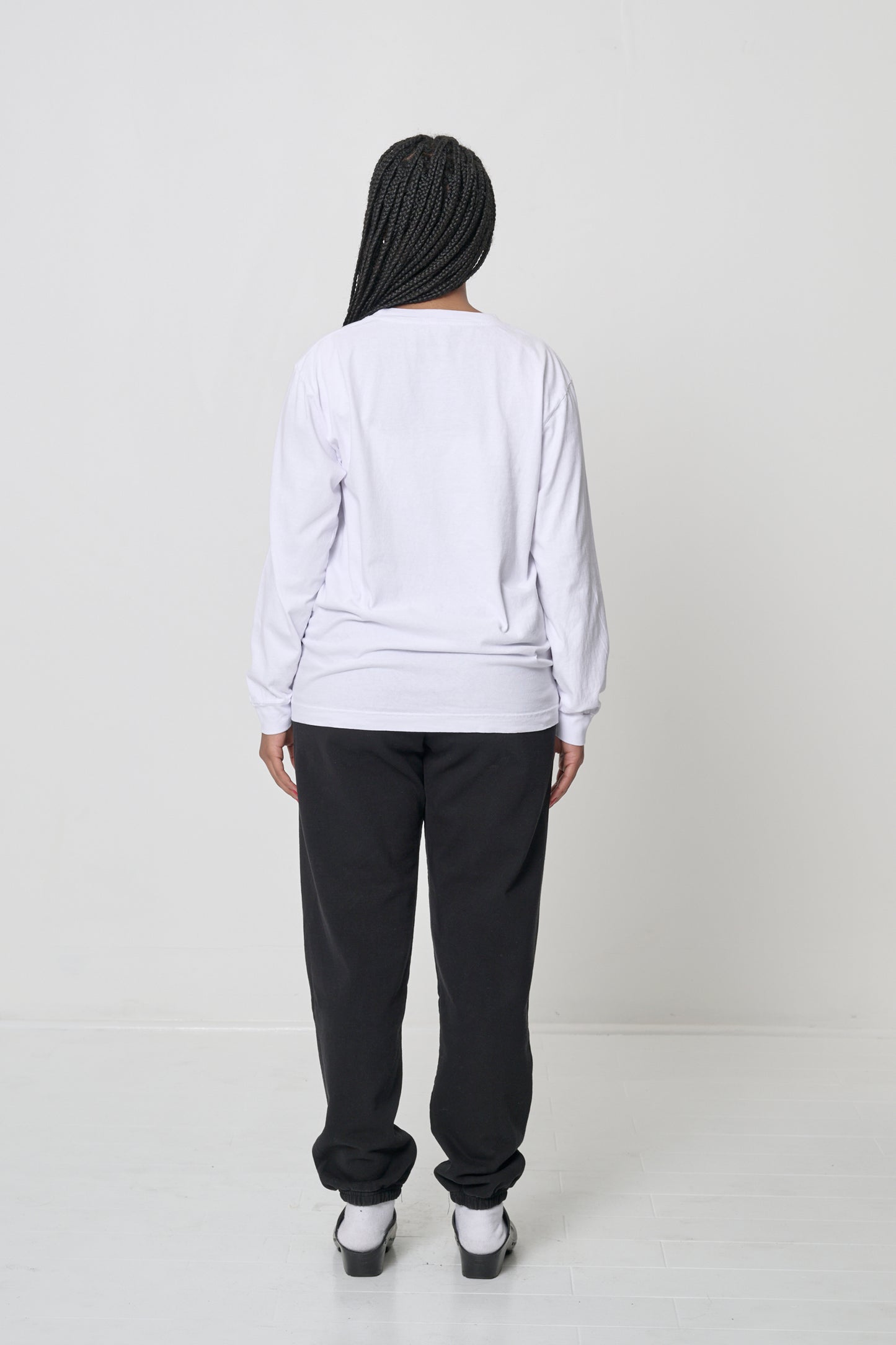 Full length back view of a person wearing a White Long Sleeve Trash Tee, with Black Trash Sweatpants.
