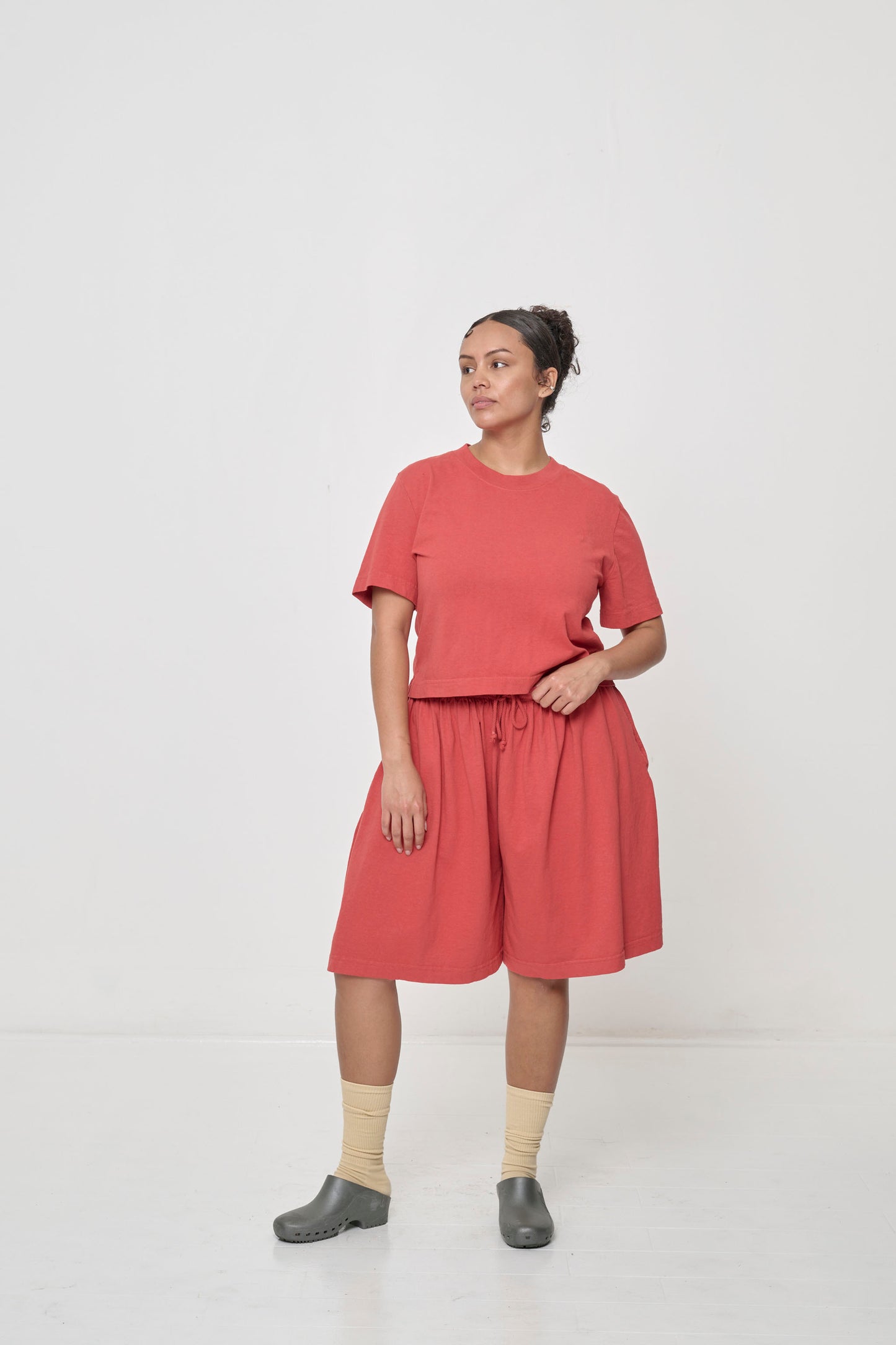 Full body front view of a 5'7" person wearing Long Tubular Shorts in Cedar. The shorts hit mid-knee and have a loose fit.