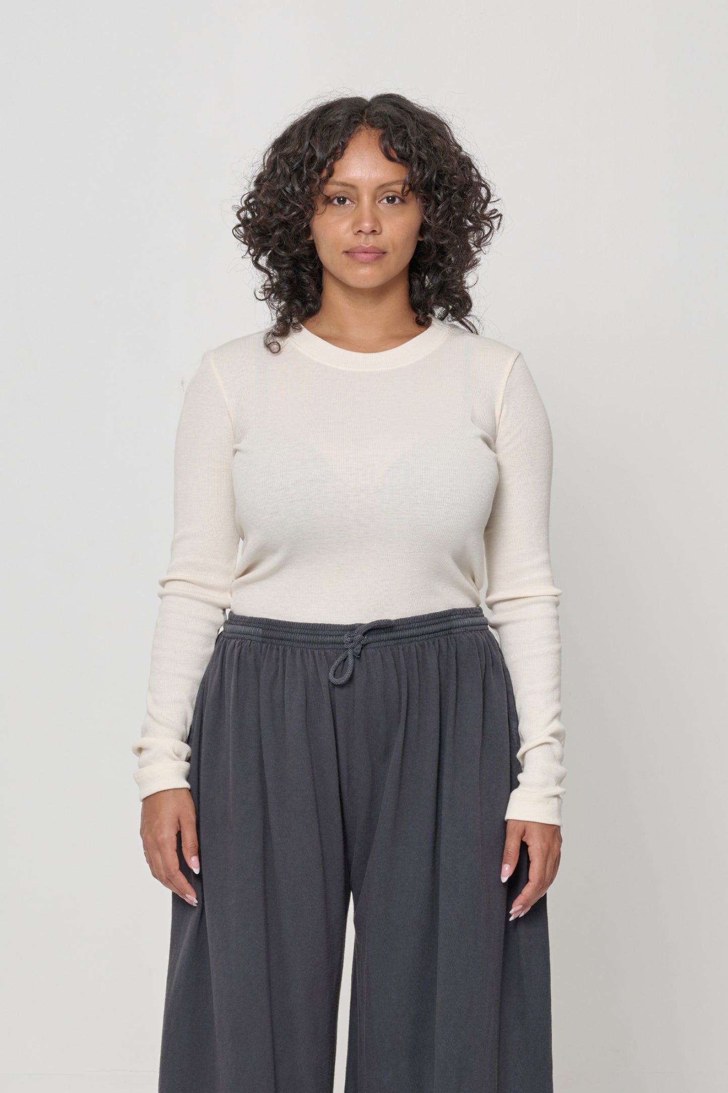 A woman wearing a Rib Long Sleeve in Natural, tucked in to a pair of Slate Tubular Pants.