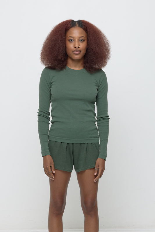 A 5'3" woman in a size S Rib Long Sleeve in Pine. Hem rests at her lower hips.