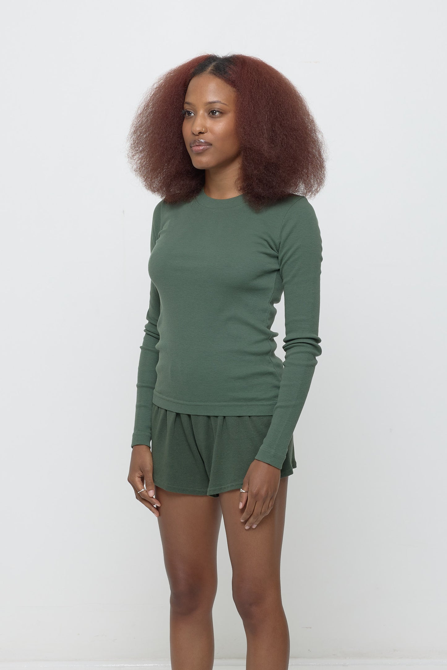 A woman turned 45-degrees from the front shows side seam and fitted silhouette.