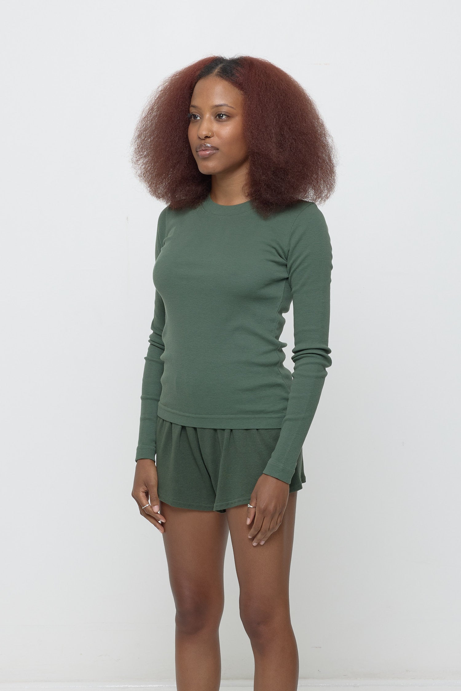 A woman turned 45-degrees from the front shows side seam and fitted silhouette.