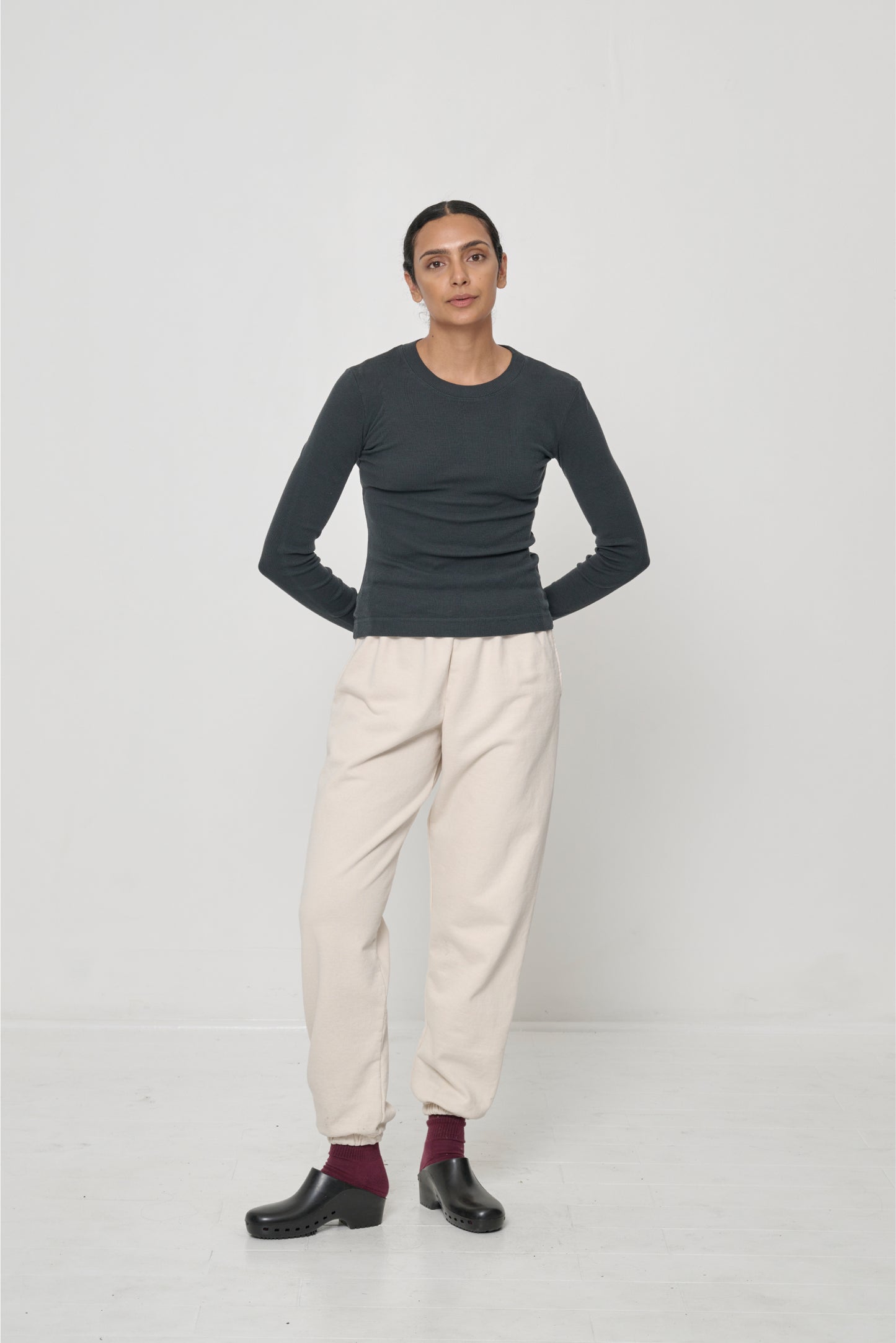 A woman in a Rib Long Sleeve in Slate, pulled over the waistband of a pair of Scour Trash Sweatpants.