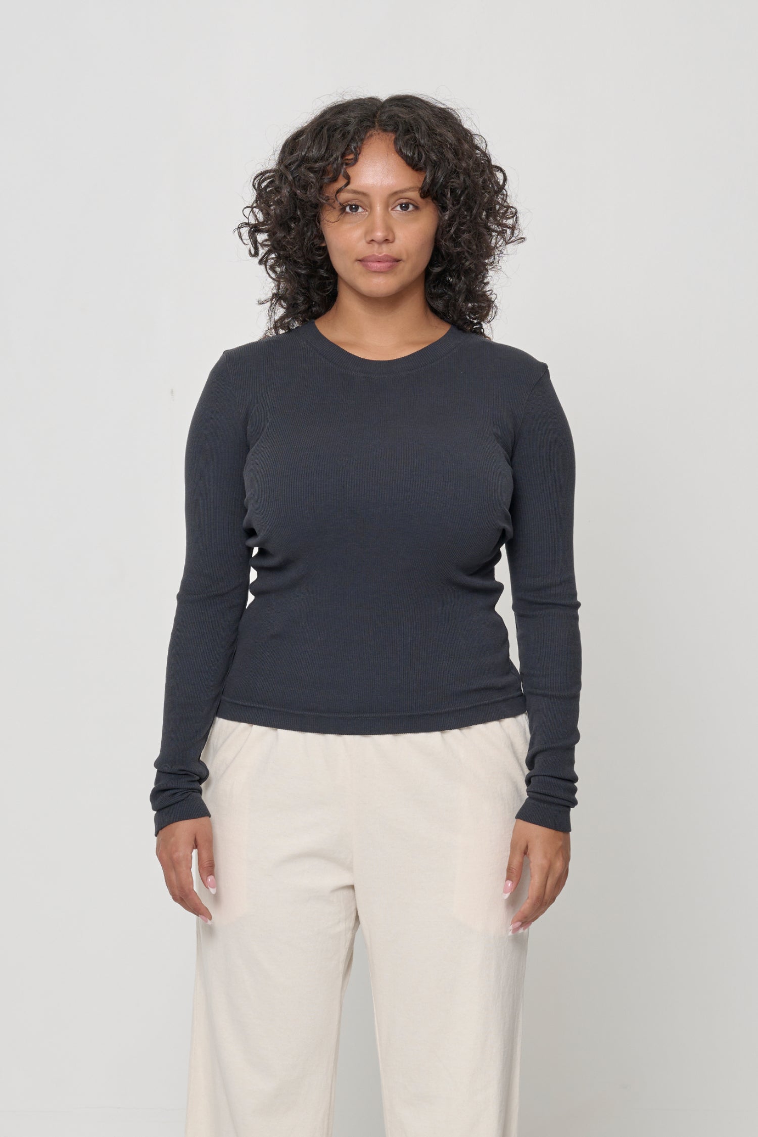 A 5'7" woman in a size M Slate Rib Long Sleeve. Heavy bottom hem hits the top of her hips.