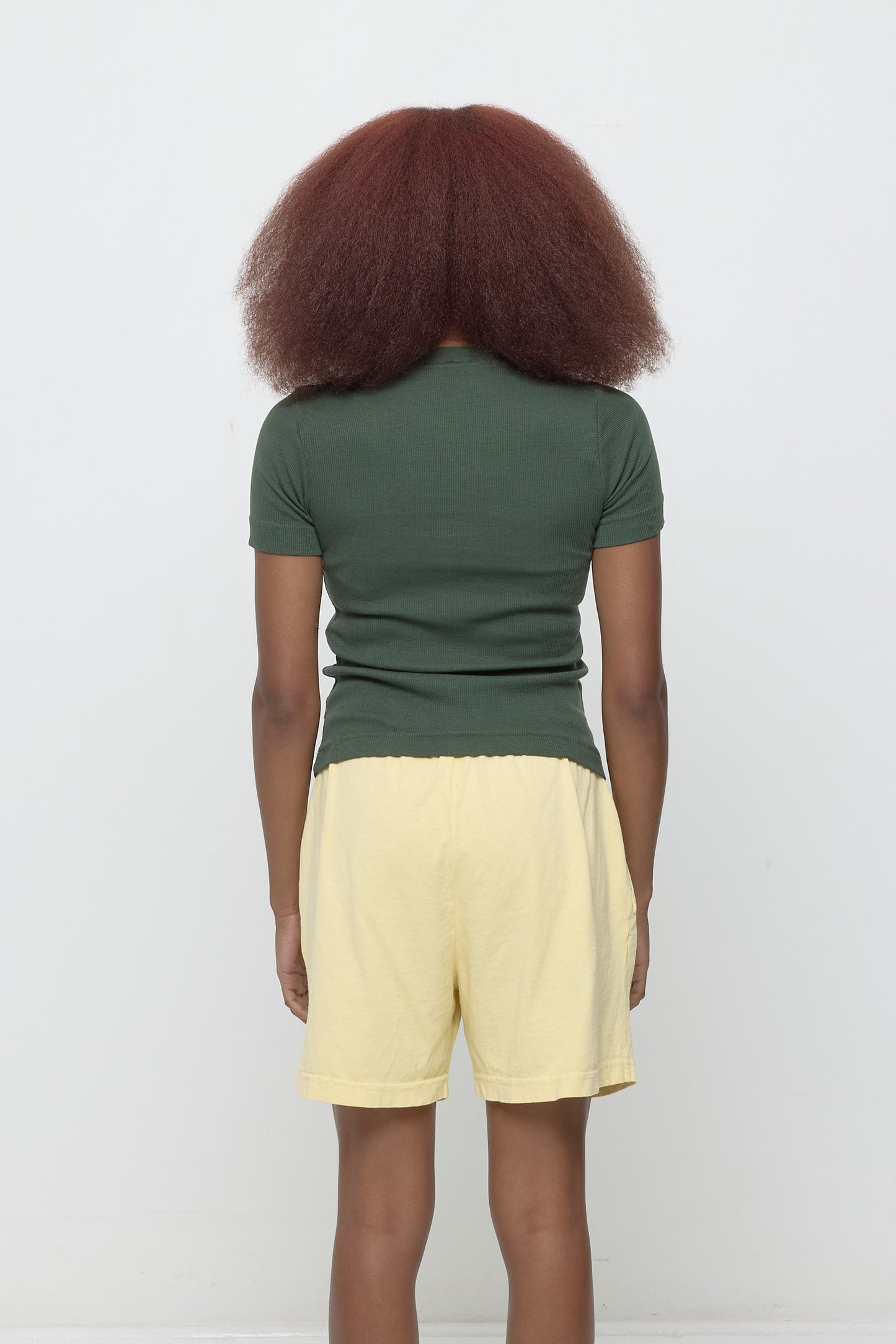 Back view: woman in Pine Rib Short Sleeve, fitted upper back, relaxed mid/lower back.