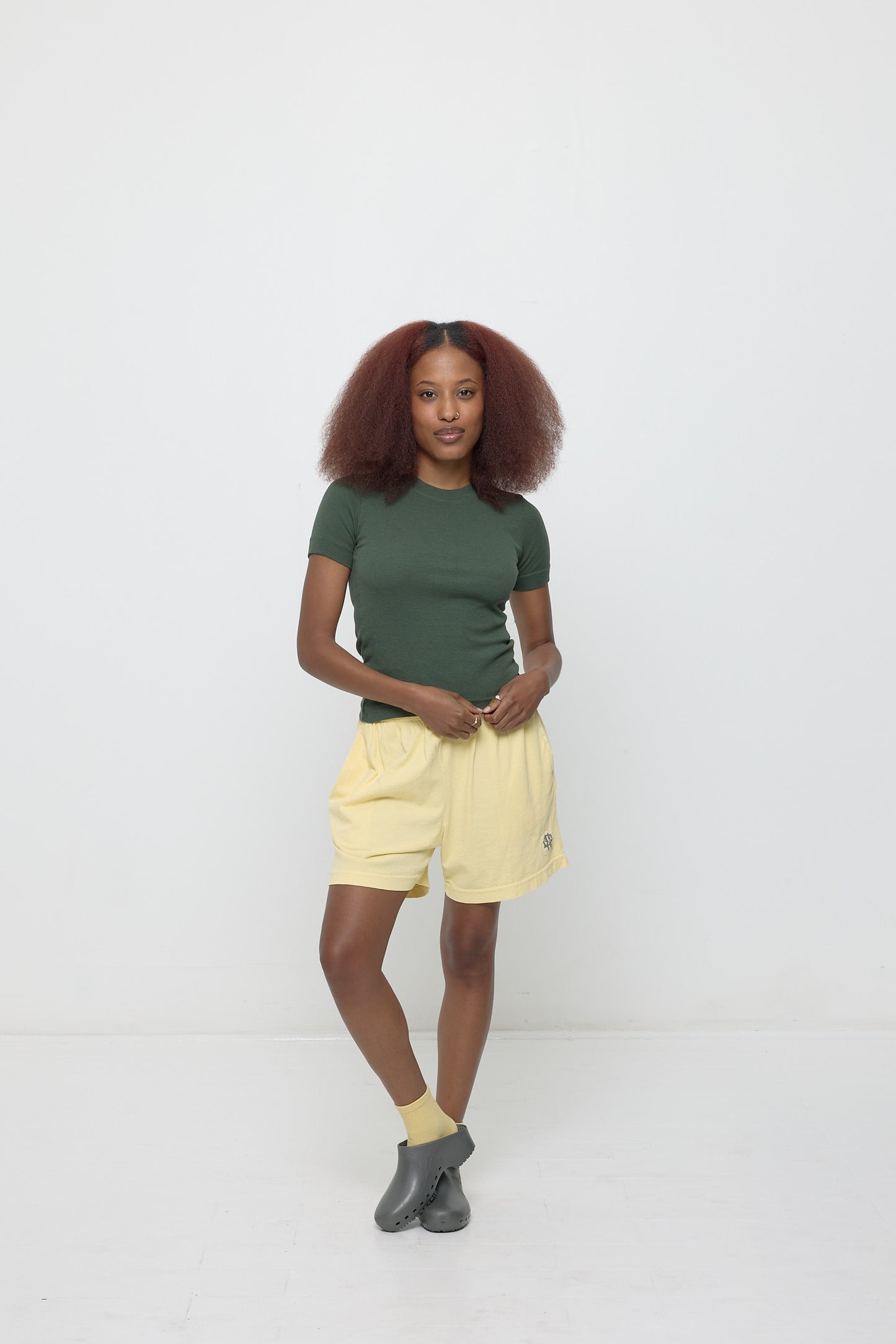 A person wearing a Rib Short Sleeve in Pine with French Butter Everyday Shorts.