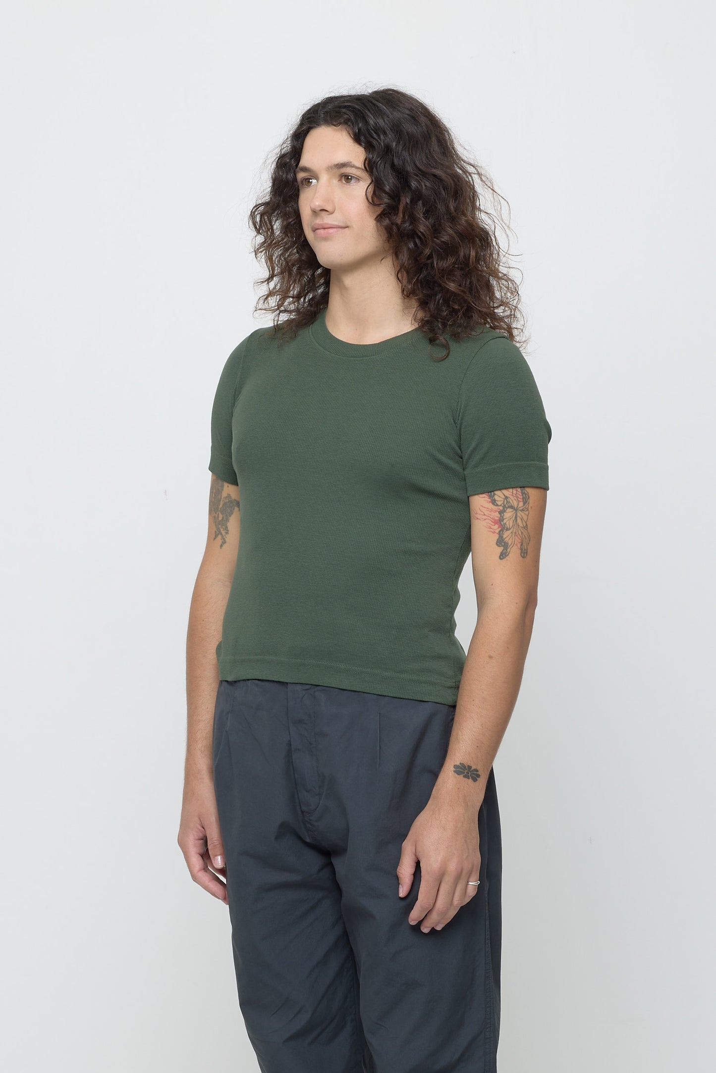 A person facing 45-degrees, in a Pine Rib Short Sleeve. Shows side seams, heavy hem, and fitted silhouette.
