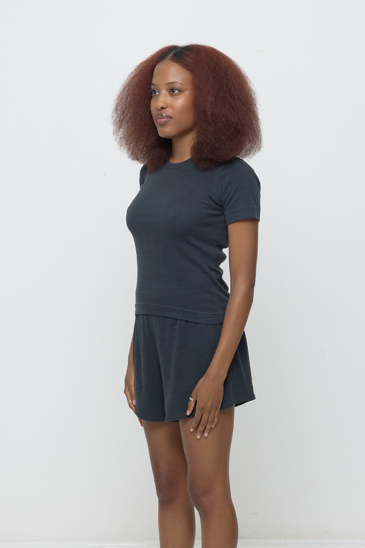 A person facing 45-degrees, in a Slate Rib Short Sleeve. Shows side seams, heavy hem, and fitted silhouette.