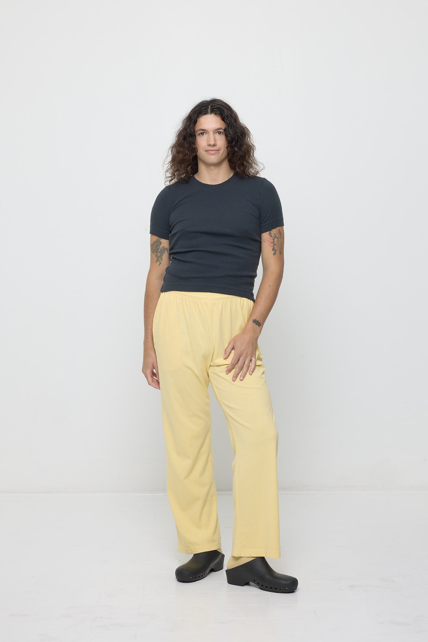 A person wearing a Rib Short Sleeve in Slate with a French Butter pair of Apartment Pants.