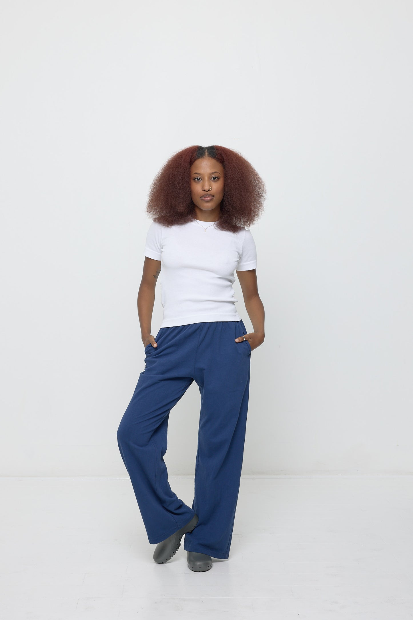 A person wearing a Rib Short Sleeve in White with Washed Navy Apartment Pants.