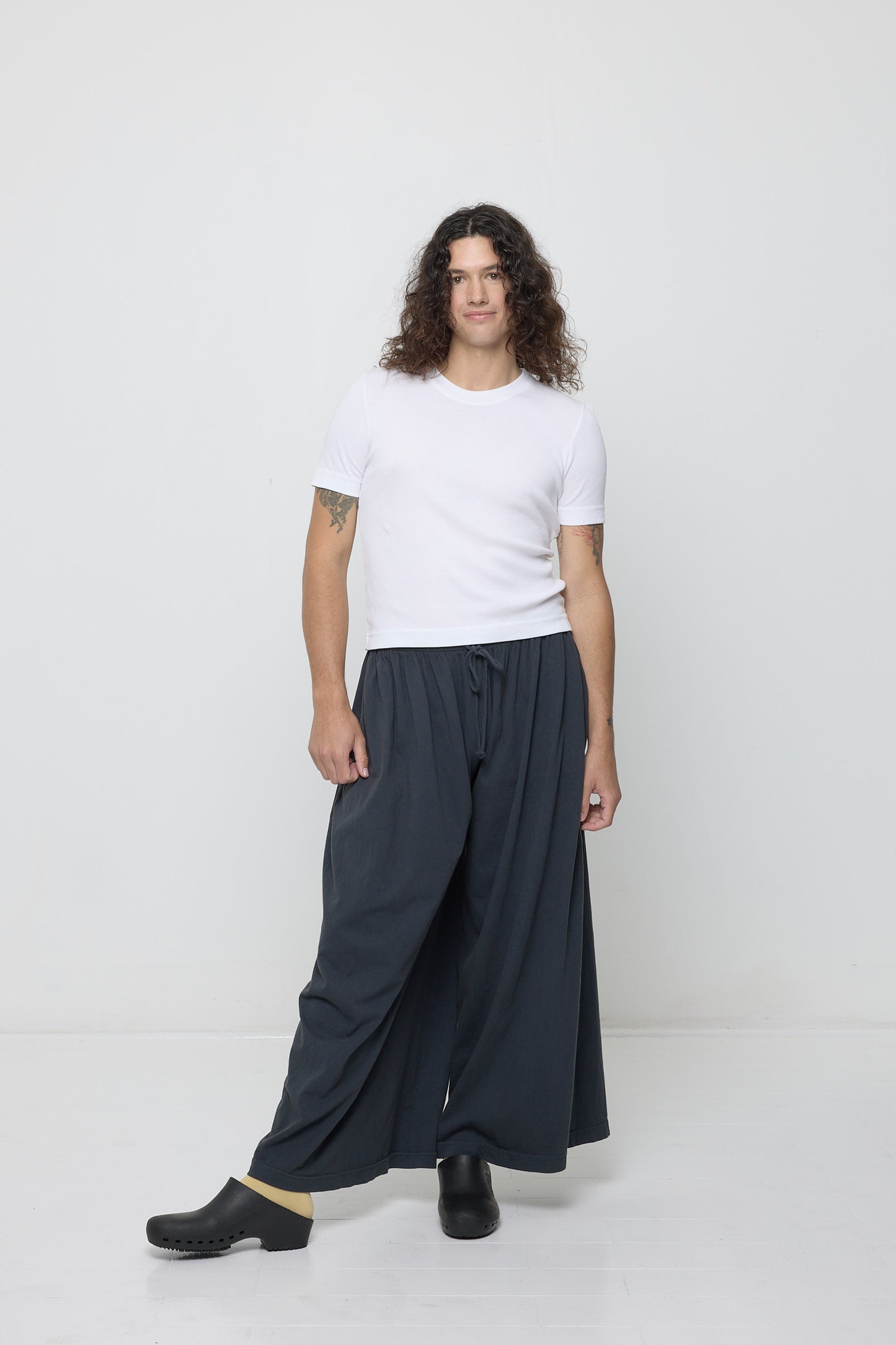 A person wearing a Rib Short Sleeve in White with Slate Tubular Pants.