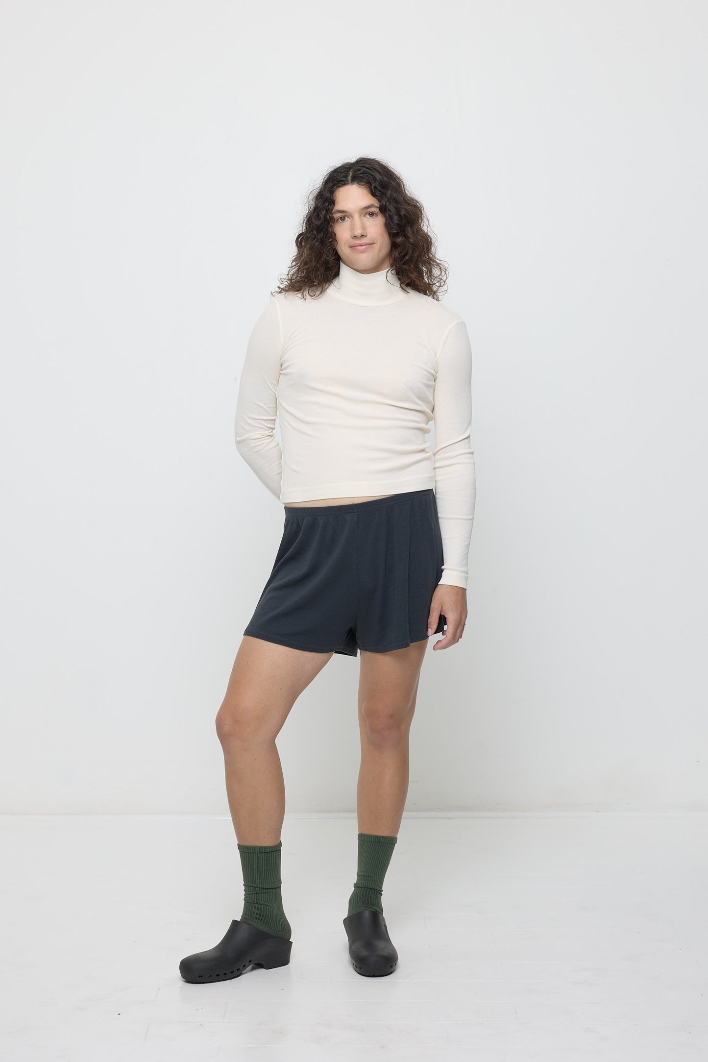 A person wearing Slate Rib Shorts with a Natural Rib Turtleneck.