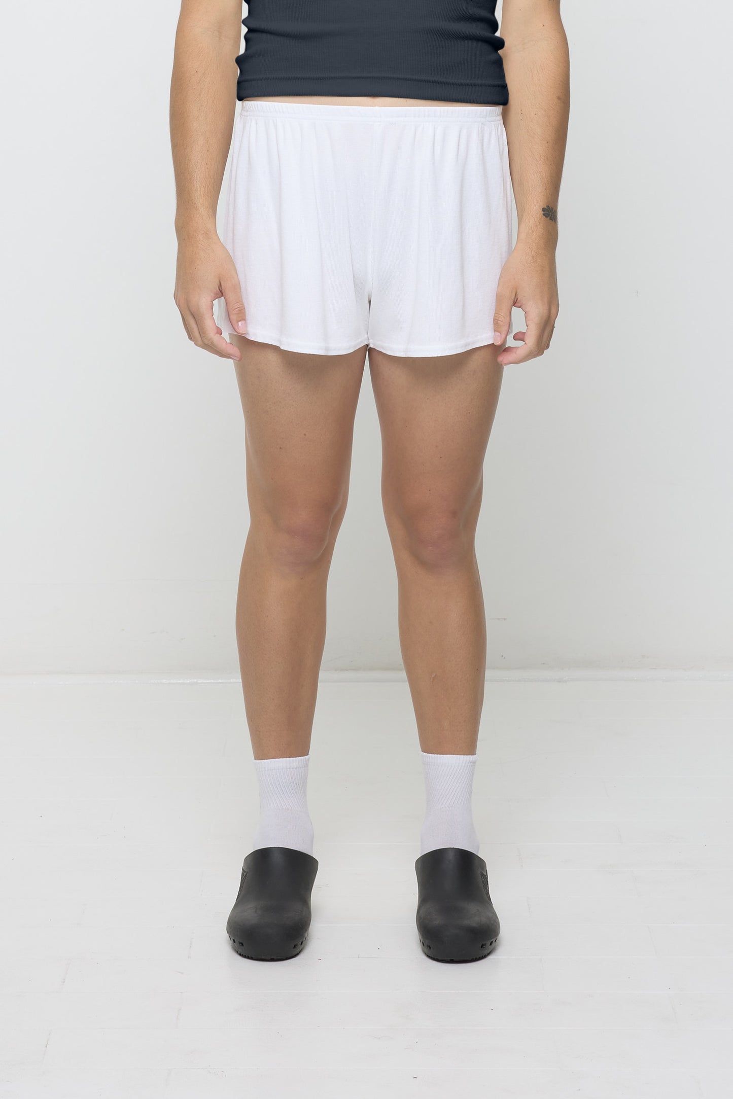 White Rib Shorts on model, waist down. Relaxed fit, upper-thigh length and elastic waist.