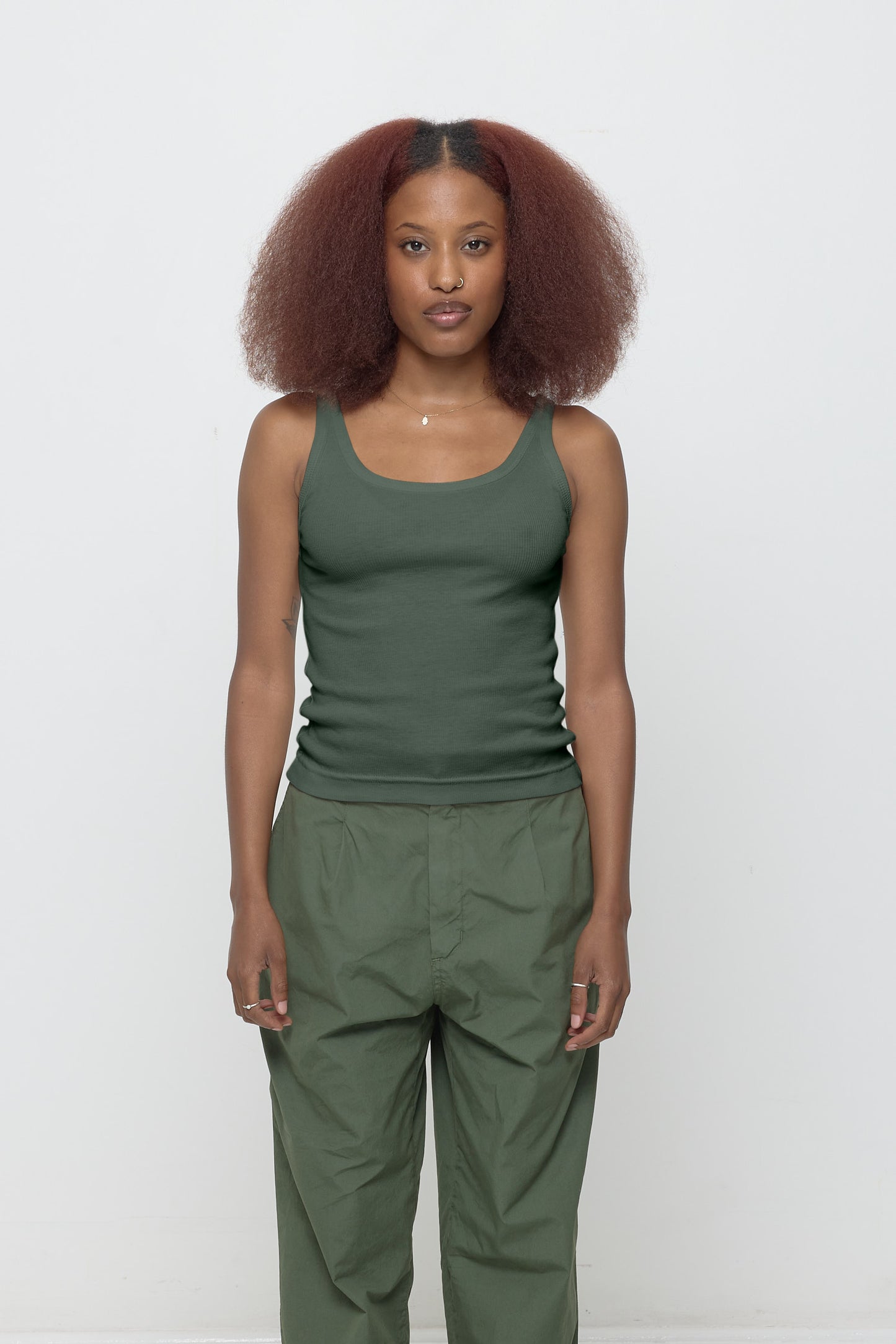 Front view of a 5'3" woman wearing a size XS Rib Tank in Pine. Hem rests on her upper hips.