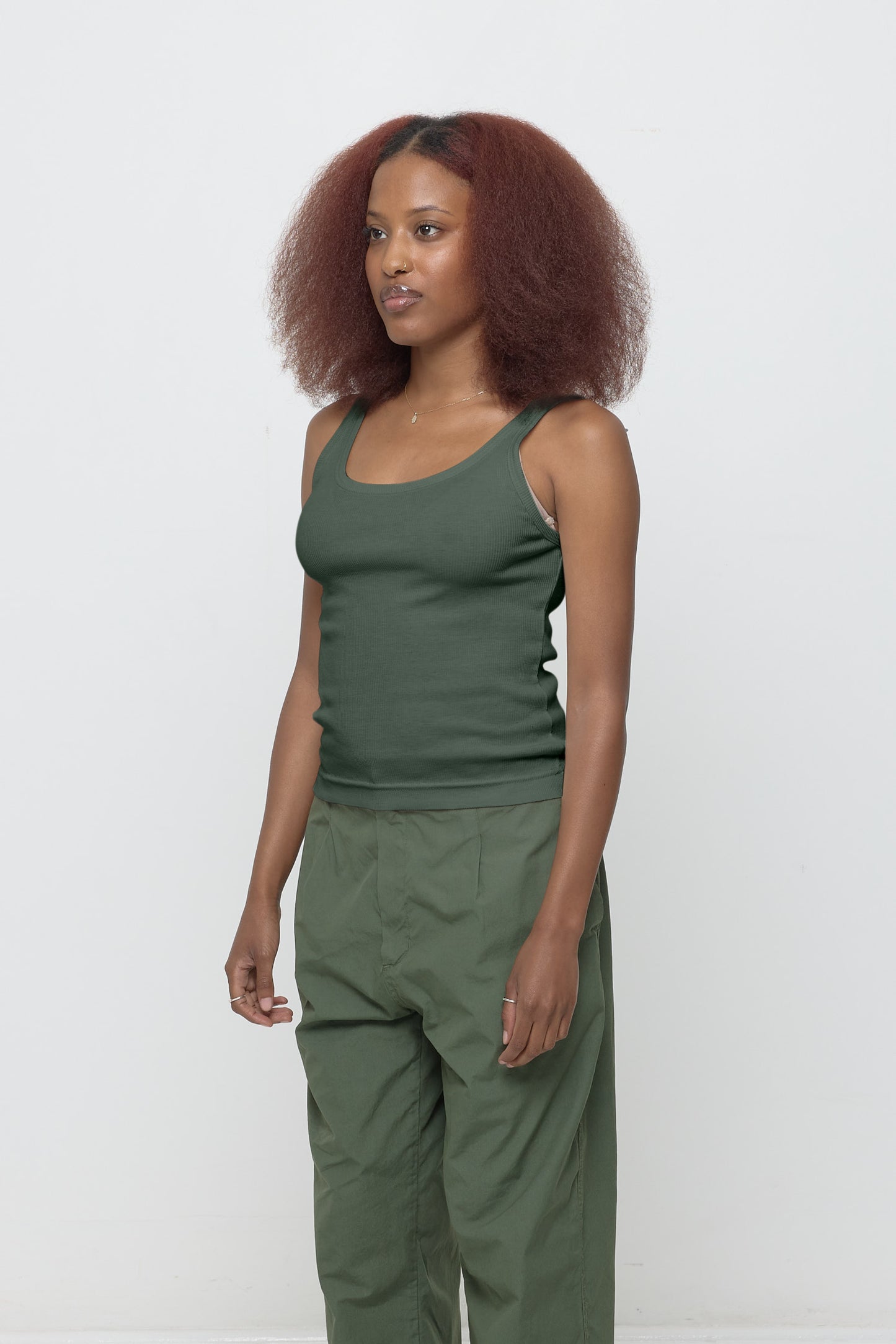 A person facing 45-degrees, wearing a Pine Rib Tank, showcasing side seams, heavy hem, and fitted silhouette.