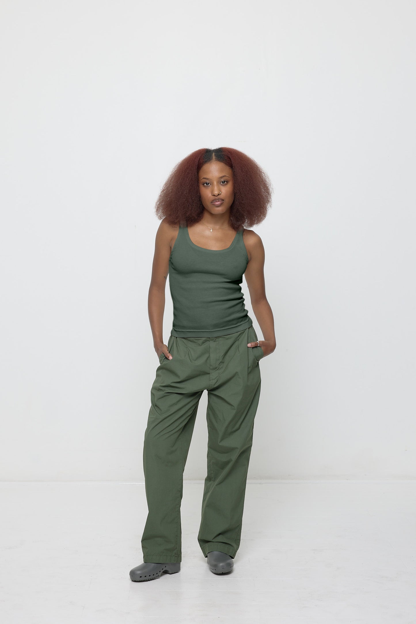 Front view of a woman wearing a Rib Tank in Pine, which just covers the waistband of her matching Life Uniform Pants.