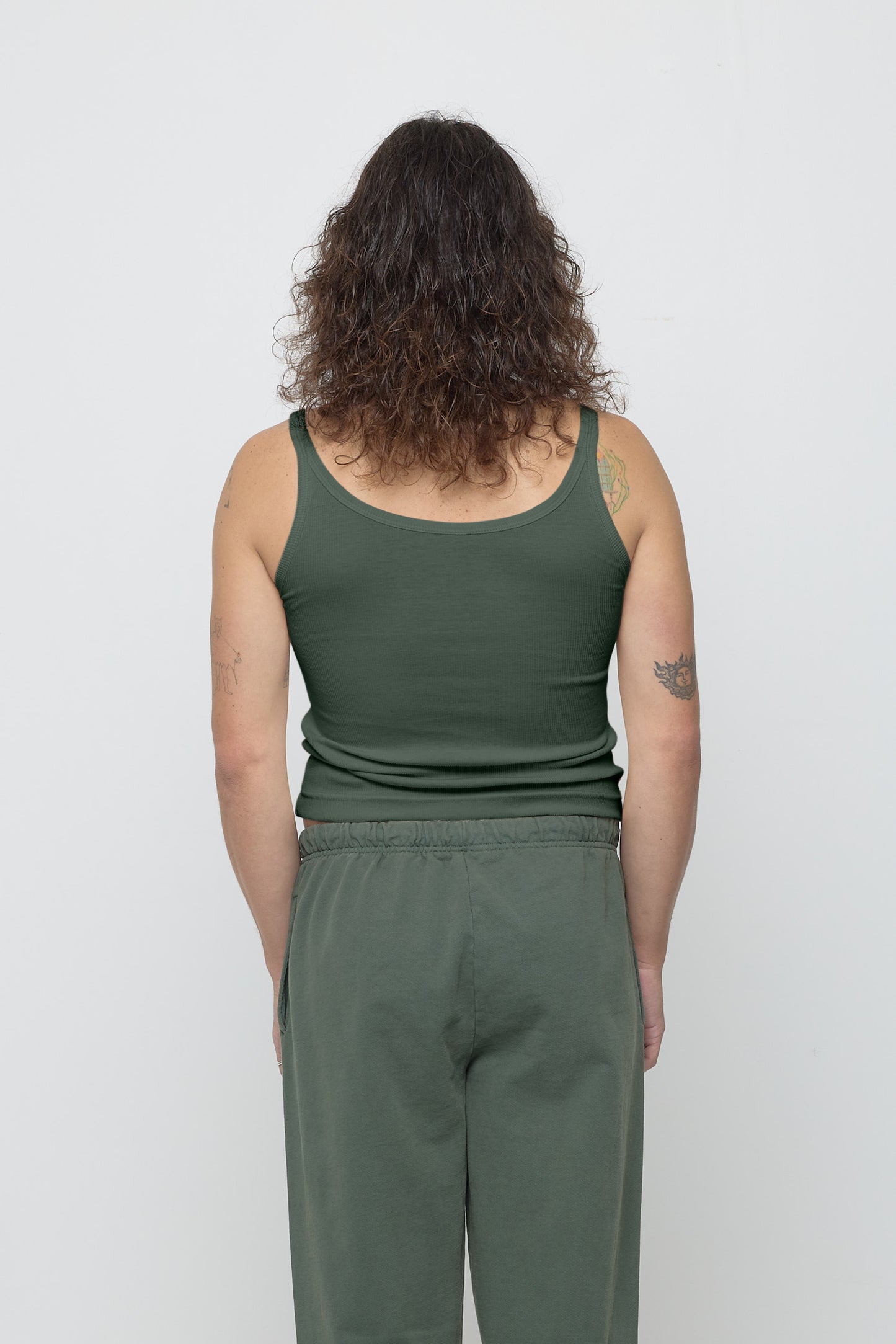 Back view: a person in Pine Rib Tank, fitted upper back, relaxed lower back.