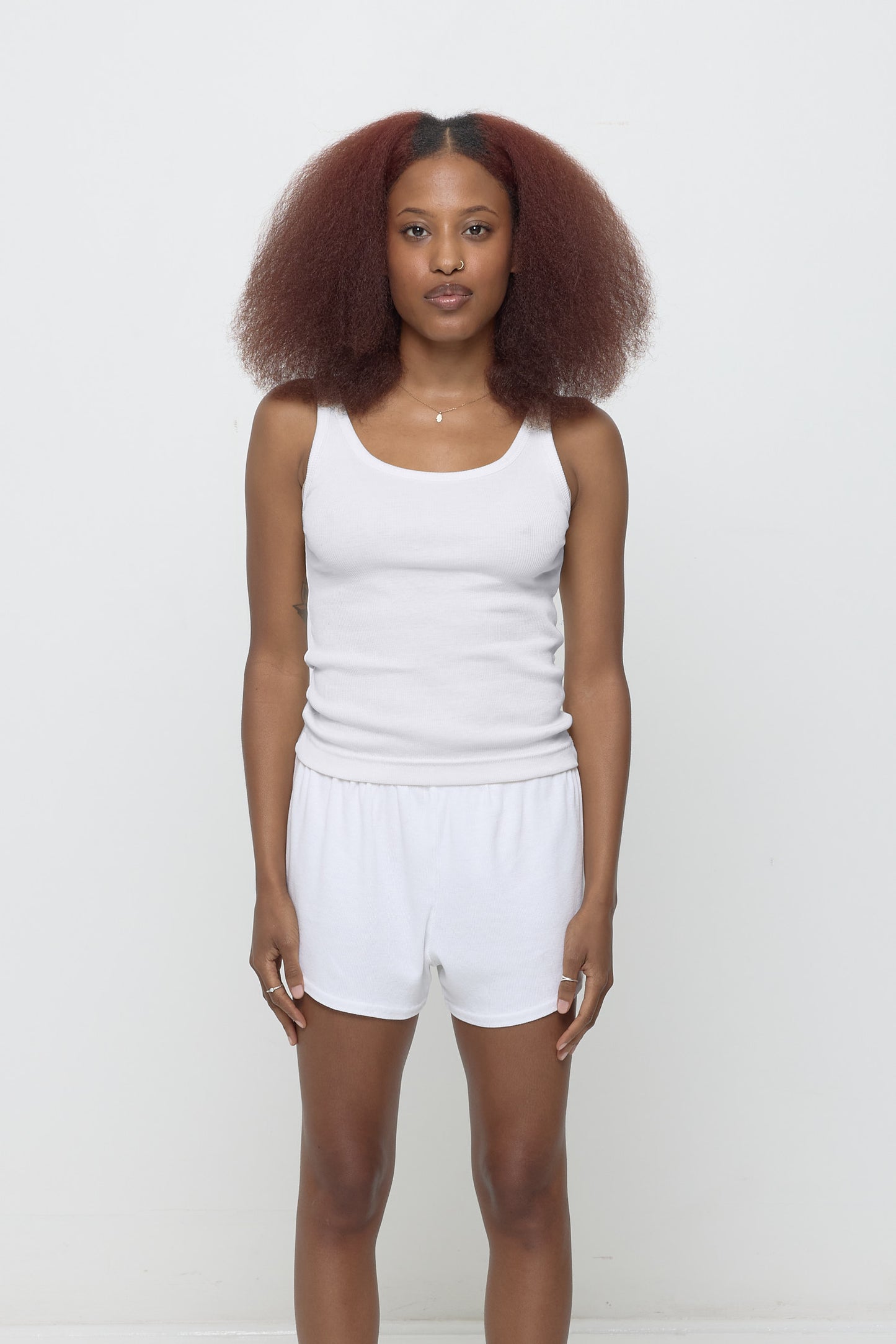 Front view of a 5'3" woman wearing a size XS Rib Tank in White. Hem rests on her upper hips.
