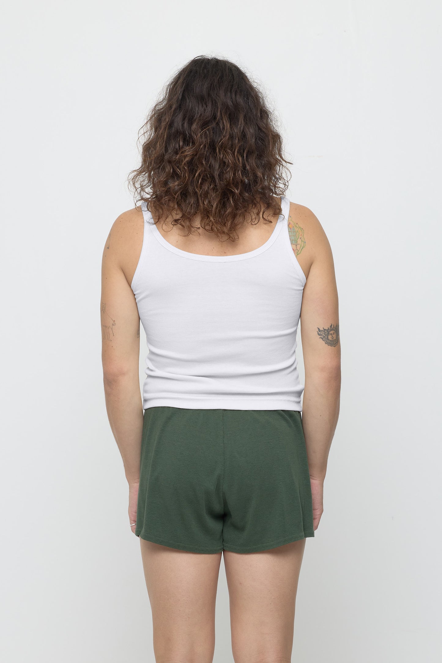 Back view: a person in White Rib Tank, fitted upper back, relaxed lower back.