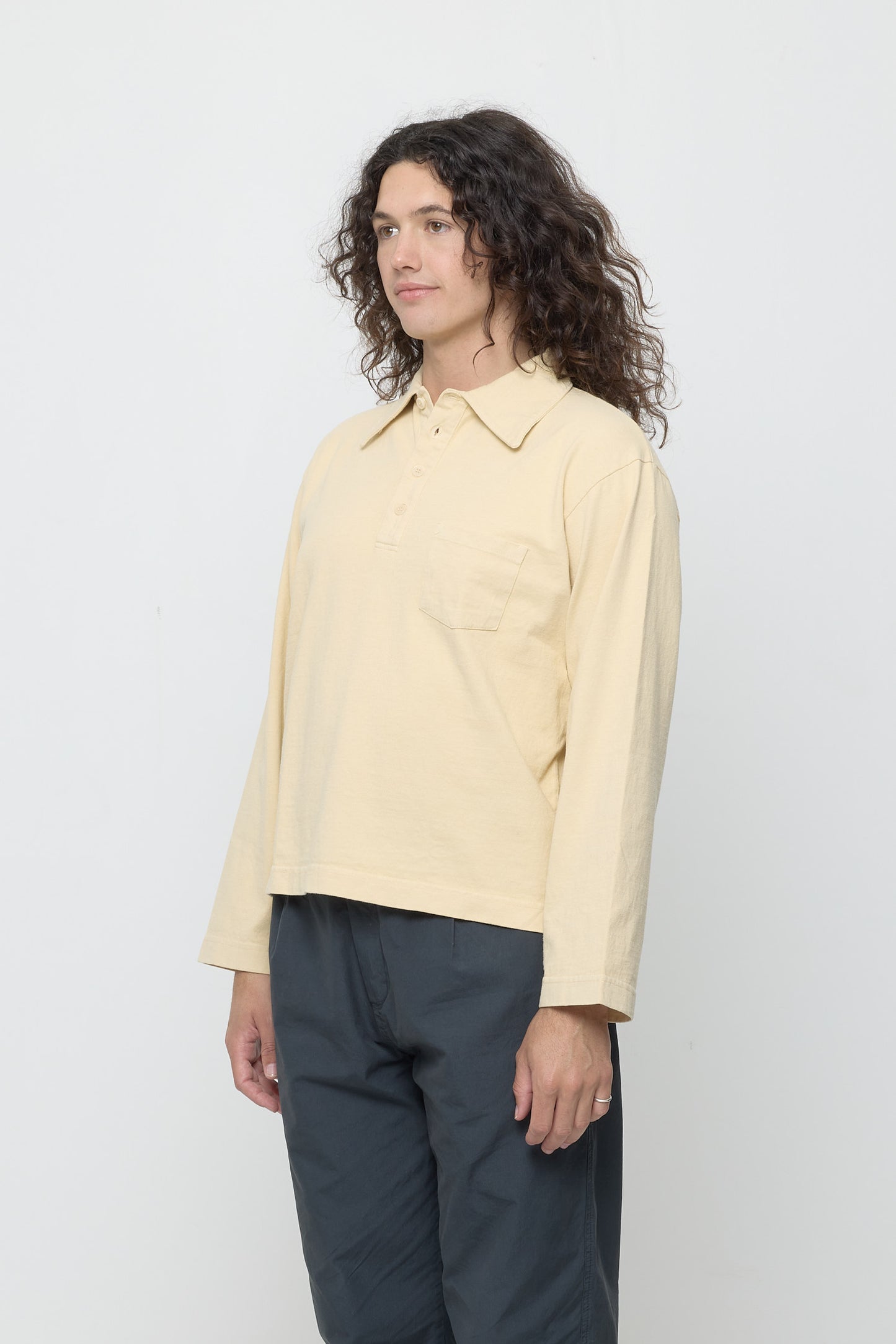 Person turned 45 degrees, wearing a Turtle Dove Rugby Trash Polo, showing relaxed sleeves.