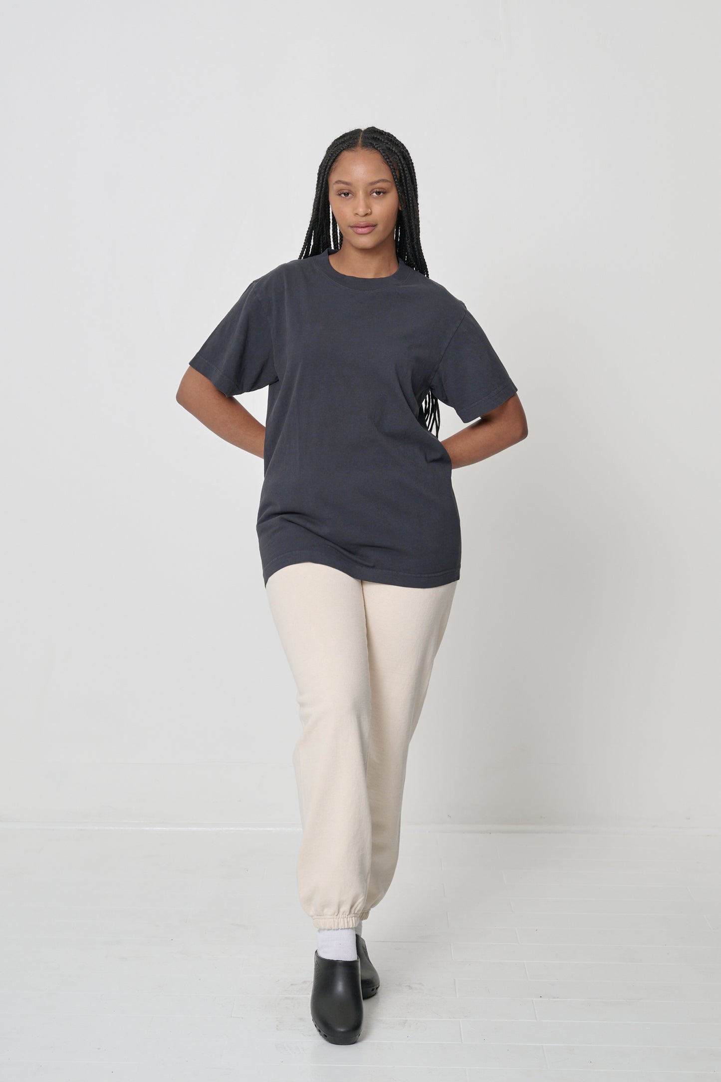 Front view of a woman wearing the Short Sleeve Trash Tee in dark gray Slate with a comfortable fit over a pair of sweatpants.