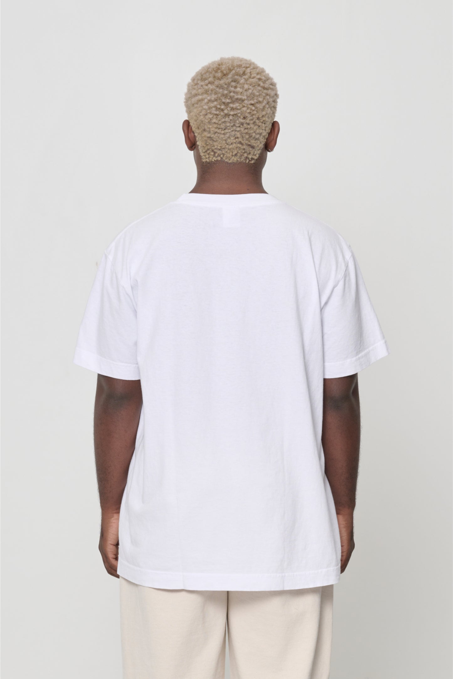 Close up back view of a man wearing the Short Sleeve Trash Tee in White, showing the back of the crew neckline.
