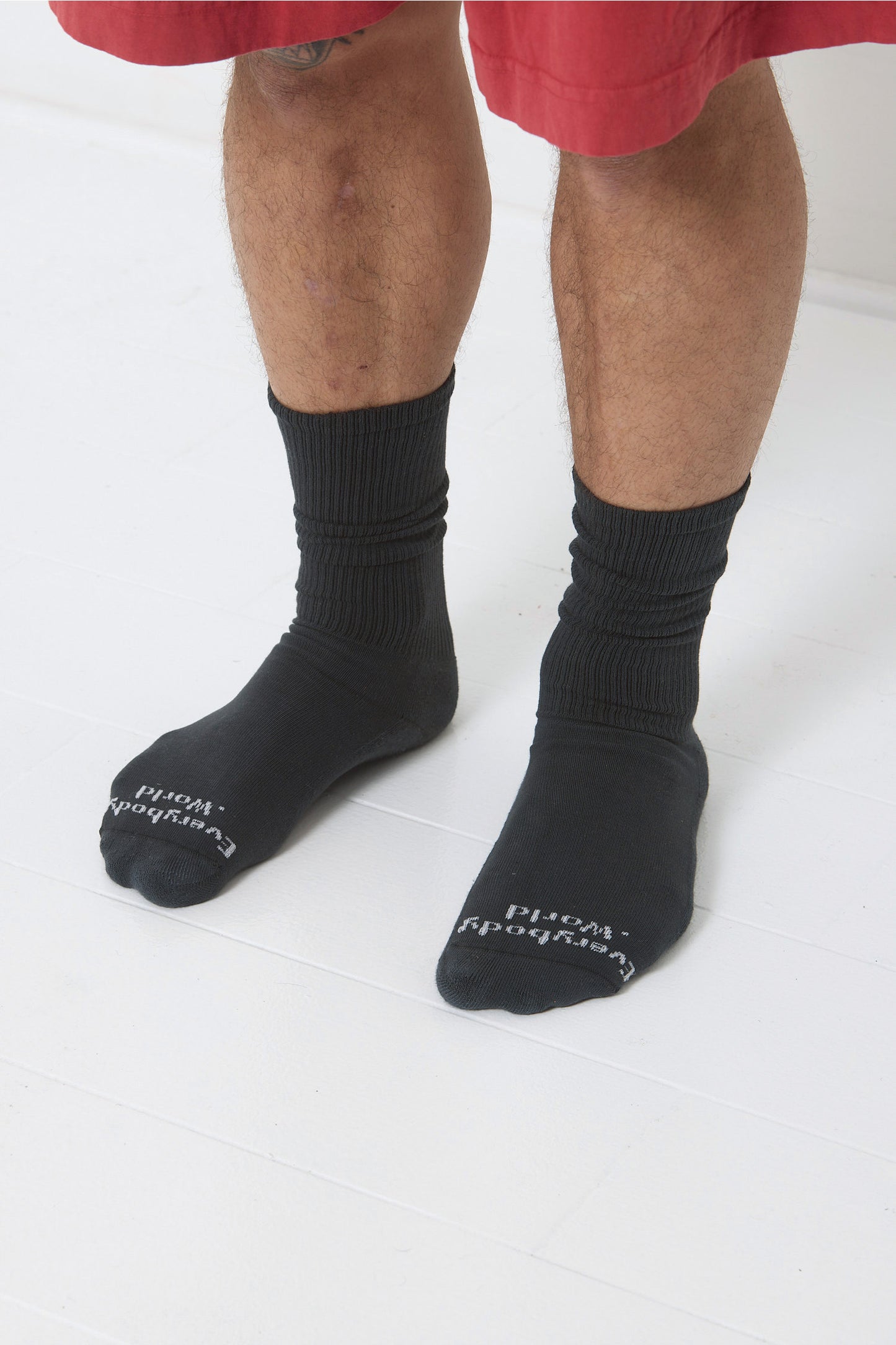 Slate Squishy Socks, branded 'Everybody.World' in white at the toe, shown on a person's lower legs.