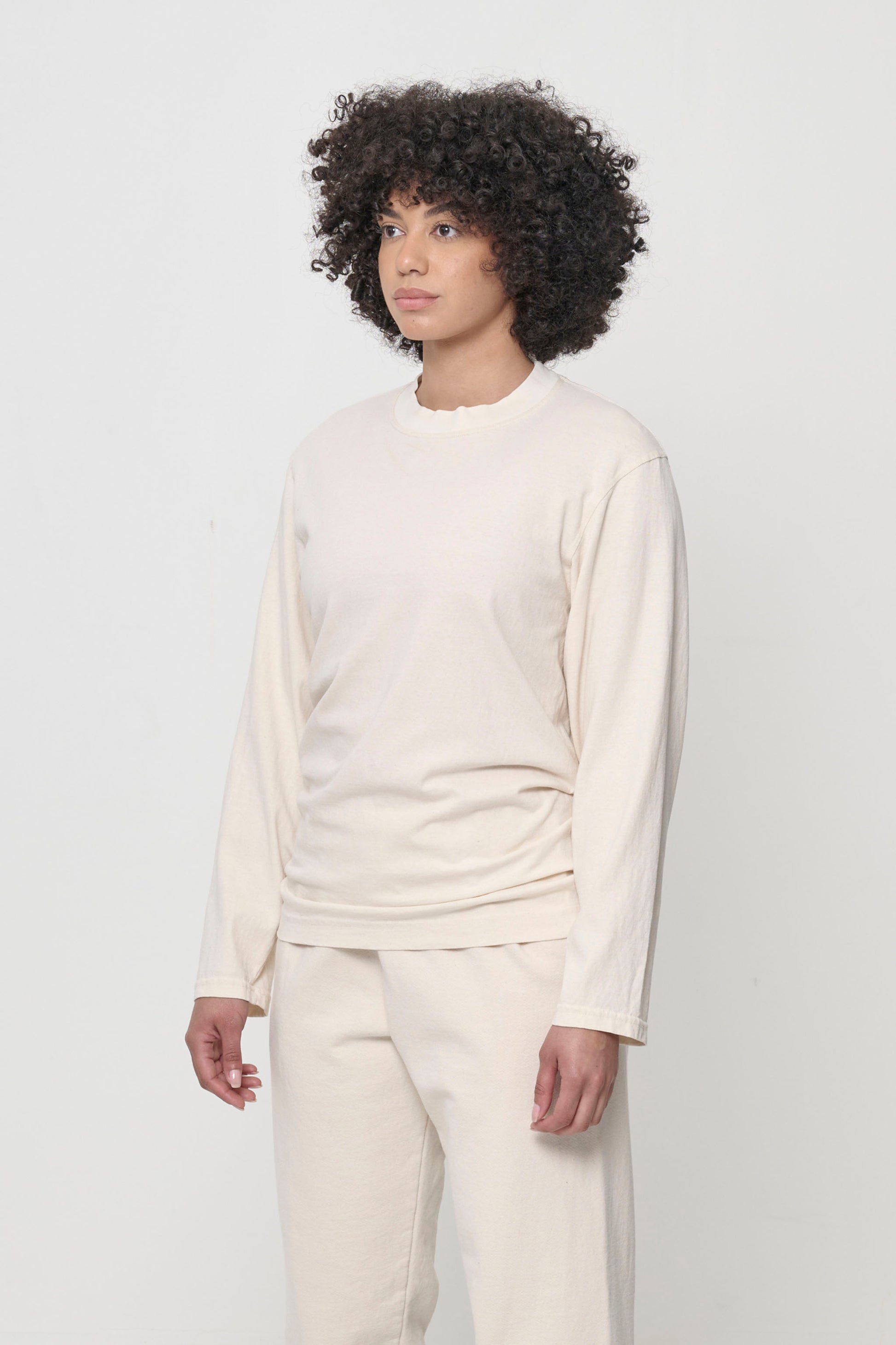 Close up 3/4 front view of a woman wearing the Straight Sleeve Trash Tee, which shows the cuff-less long sleeves.