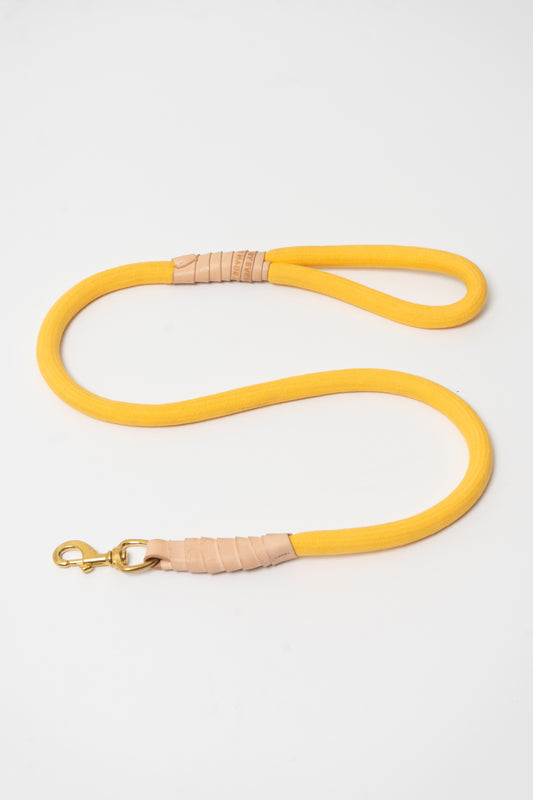 Flat lay of Everybody Yellow Super Leash positioned in an s-shape, with a solid brass clip and vegetable-tanned leather accents.