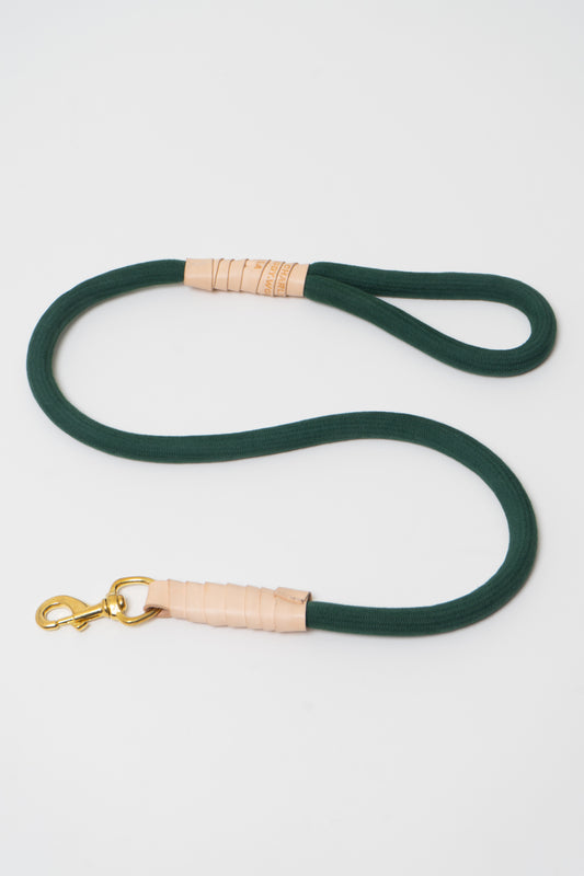 Flat lay of Moss green Super Leash positioned in an s-shape, with a solid brass clip and vegetable-tanned leather accents.