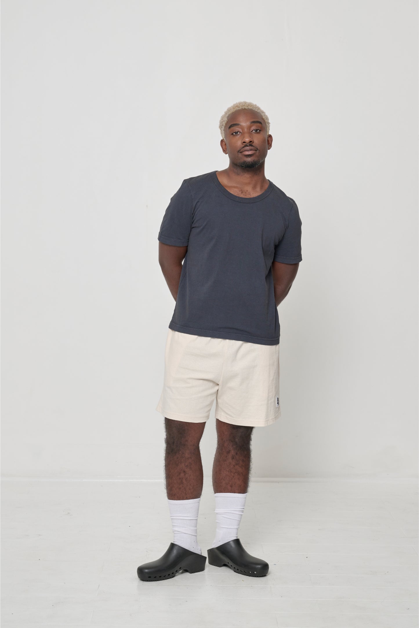Person wearing a Slate Tailored Trash Tee with Scour Everyday Shorts, White Squishy Socks and Black Calzuro Classic Clogs