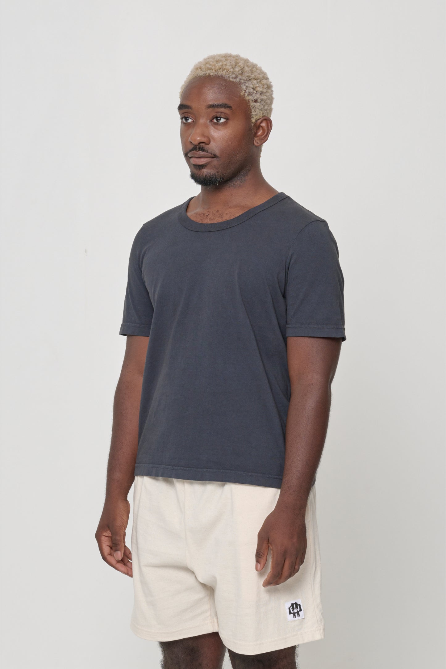 Tailored Trash Tee in White - 3/4 front view on person, showcasing slim short sleeves.