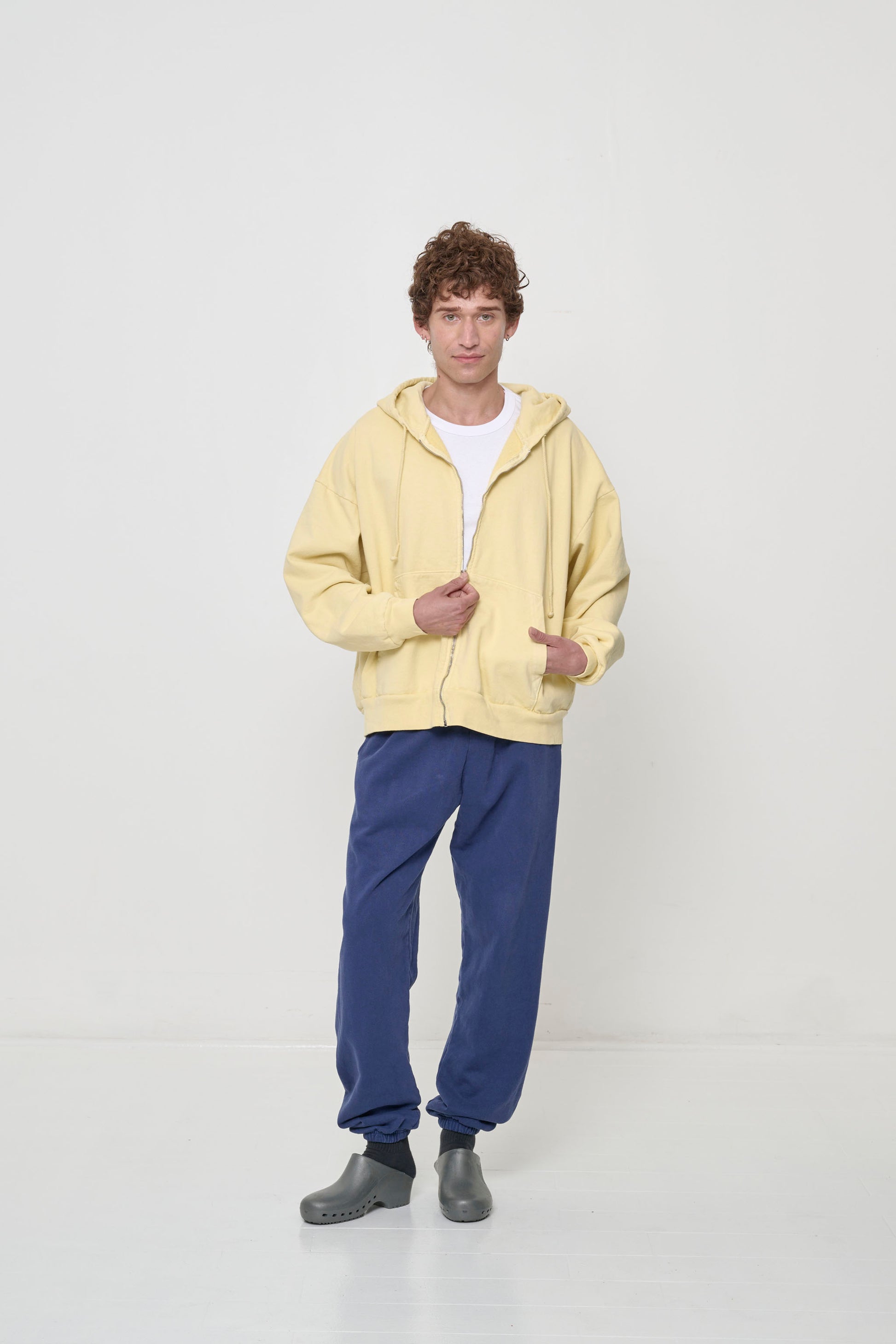 Person wearing White Tailored Trash Tee under a French Butter Trash Zip Up Hoodie and Washed Navy Trash Sweatpants