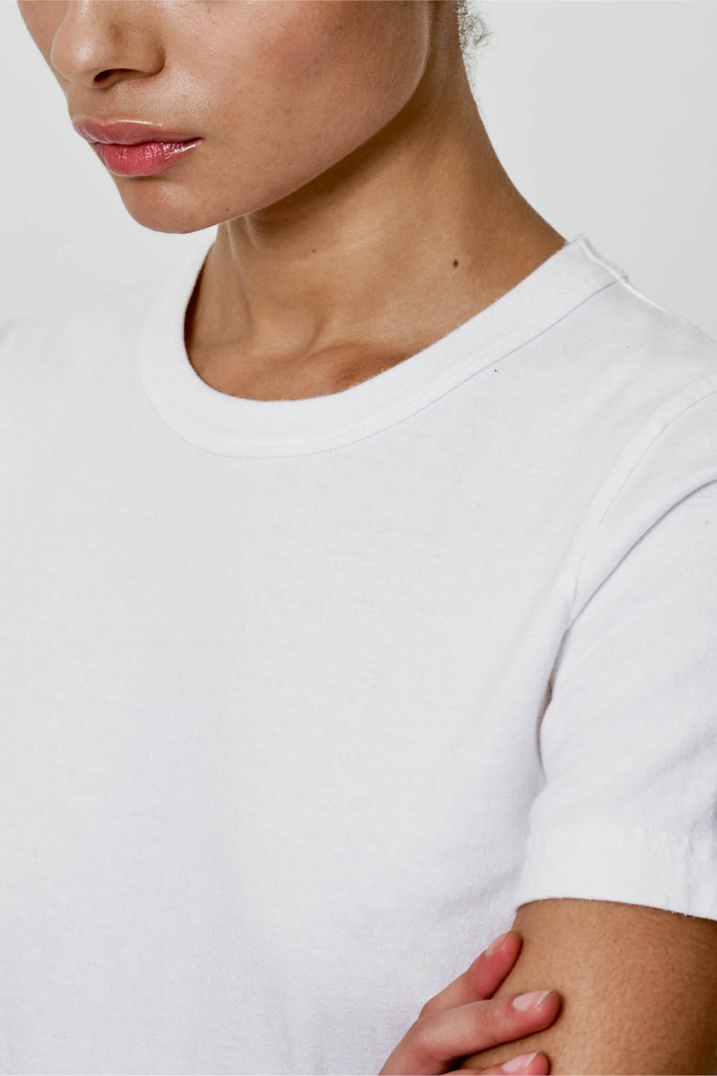close up: a woman in a White Tailored Trash Tee highlighting rib binding neckband and sleeve hem
