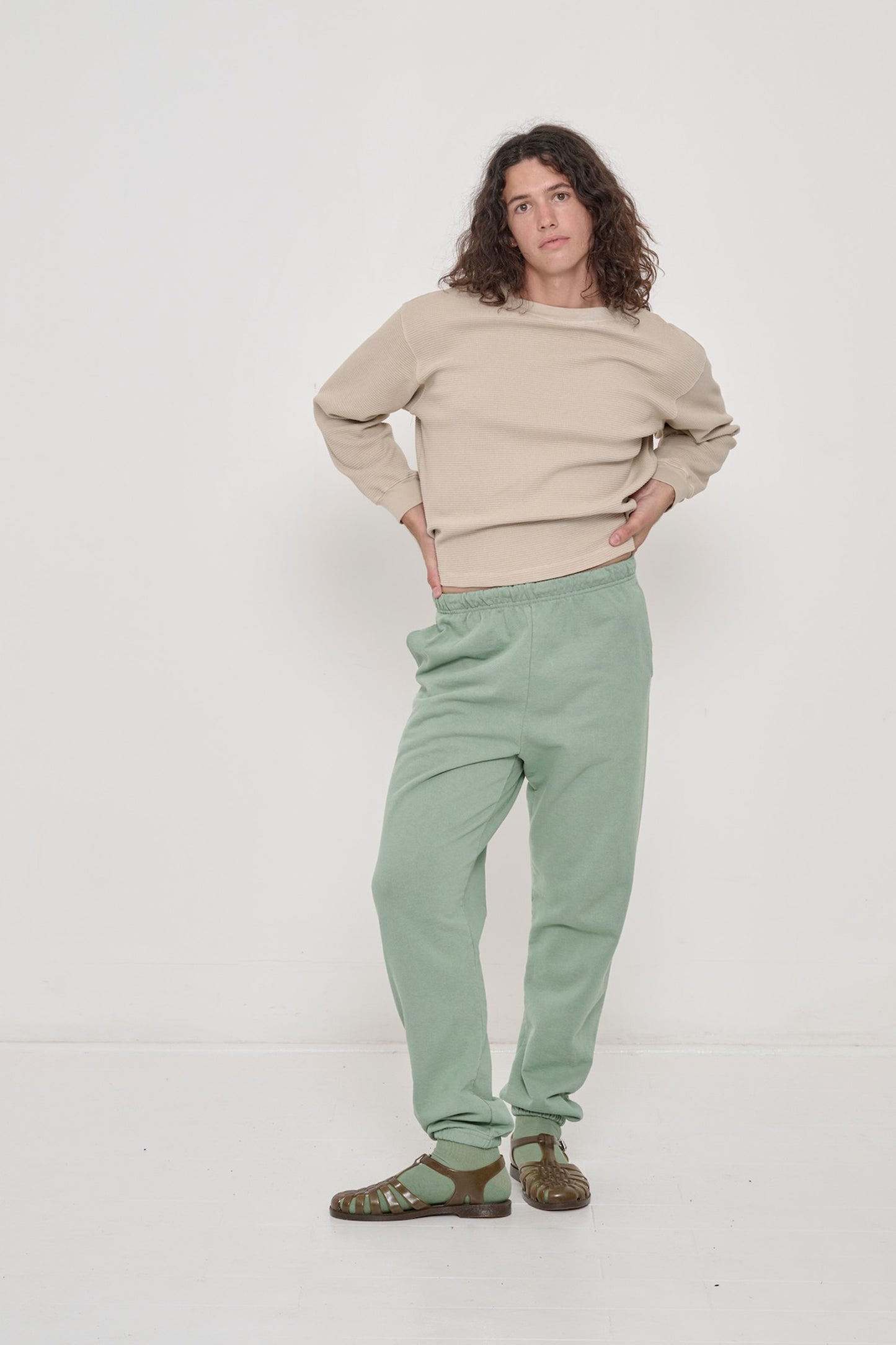 A person in an Oat Thermal Long Sleeve Boxier Trash Tee. Casually styled with Trash Sweatpants and Plasticana Jellies.