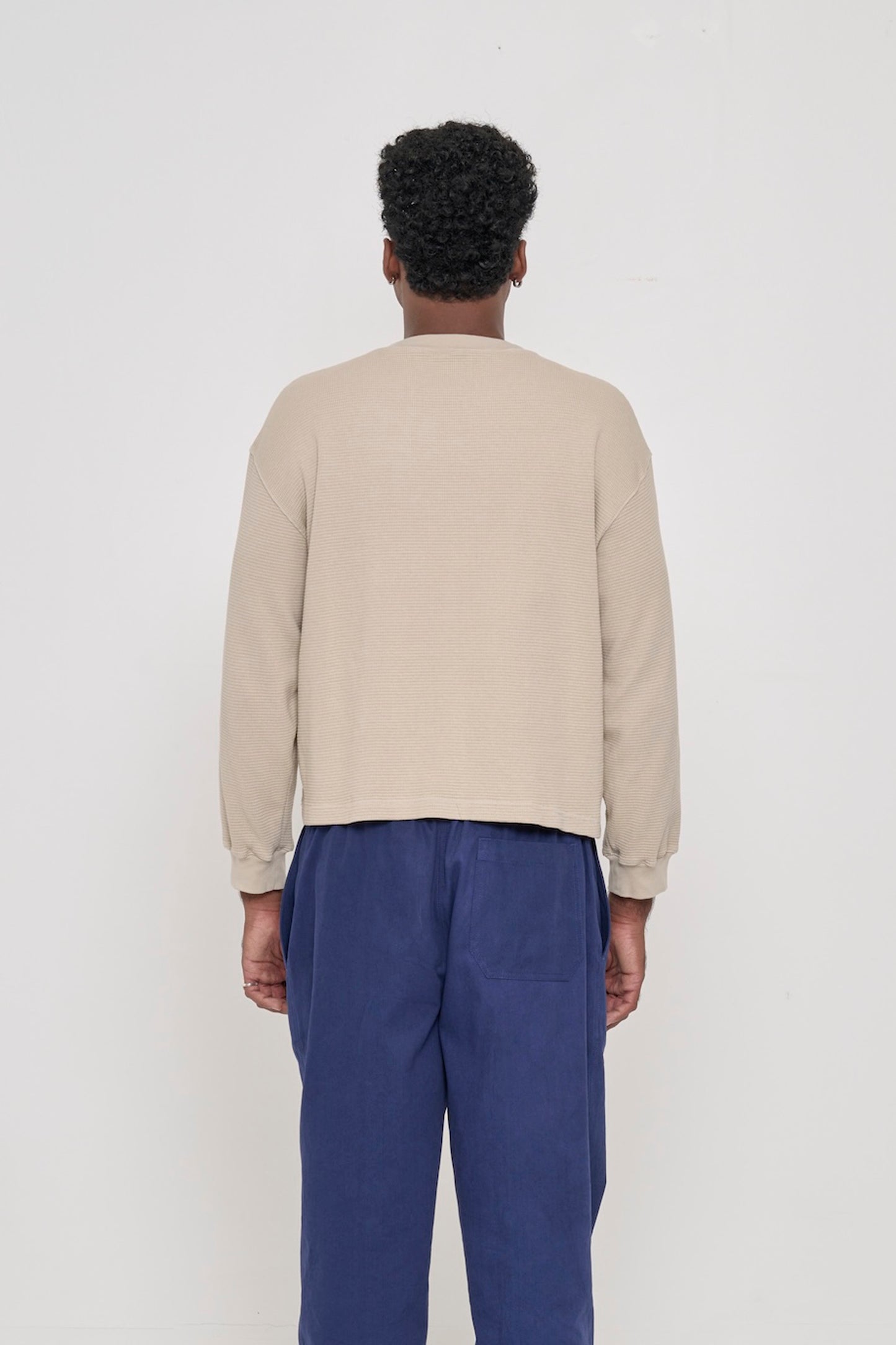Back view of person in Oat Thermal Long Sleeve Boxier Trash Tee showing the relaxed drape of the fabric.