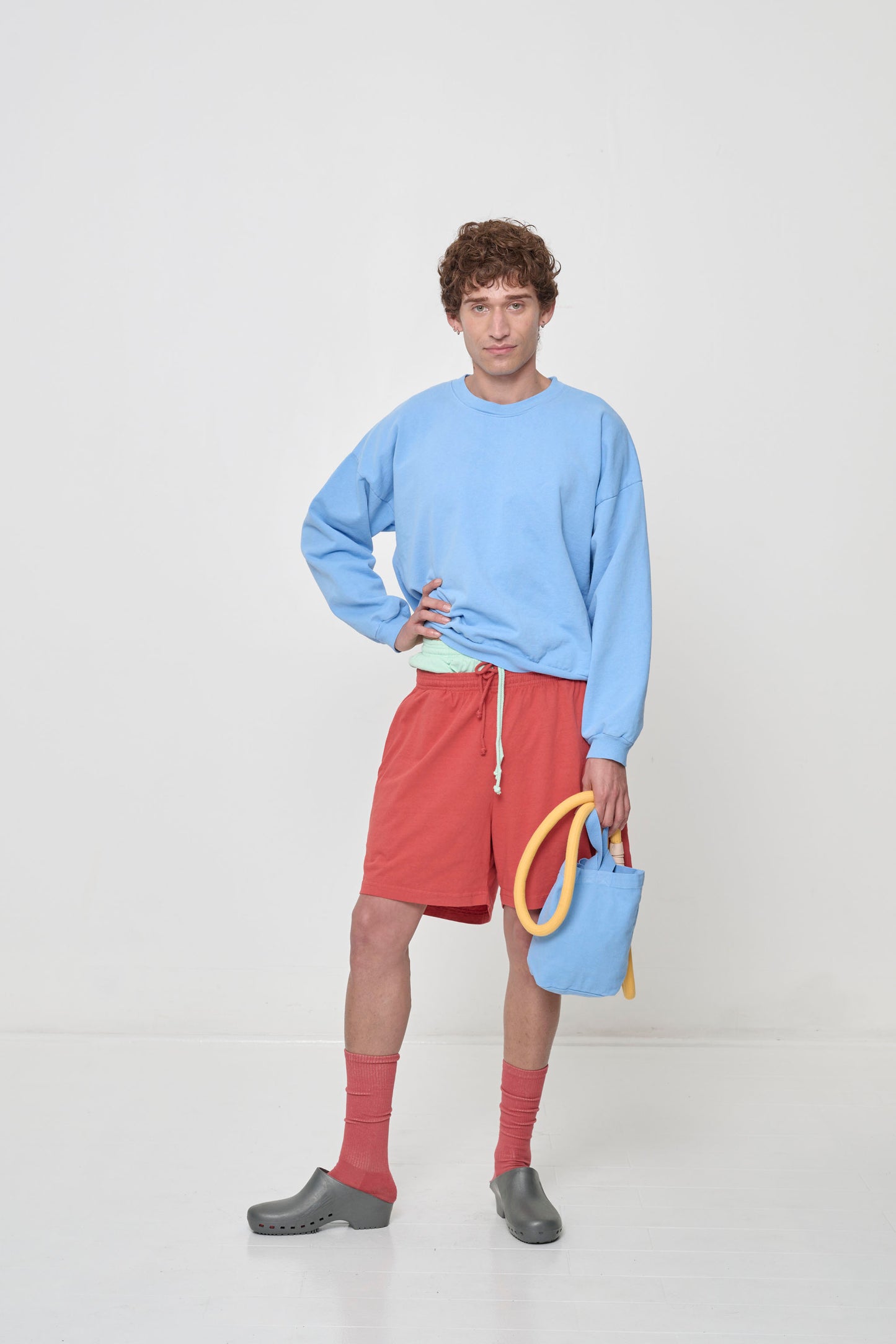 Front full length: person in Cielo Trash Crewneck and Cedar Everyday Shorts, with a Super Leash and Loop Tote in one hand.