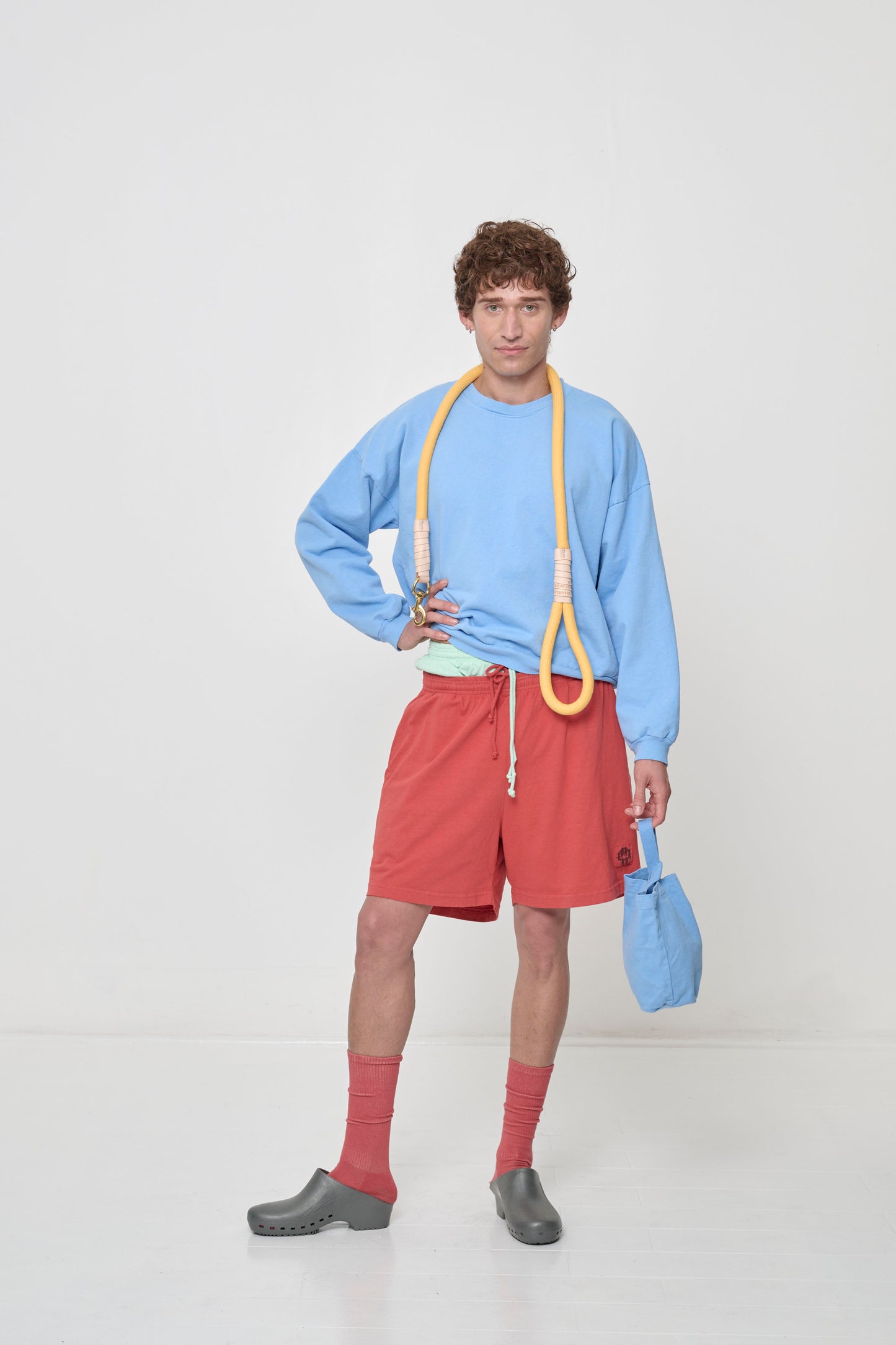 Front full length: person in Cielo Trash Crewneck and Cedar Everyday Shorts, with a Super Leash slung around the back of their neck.