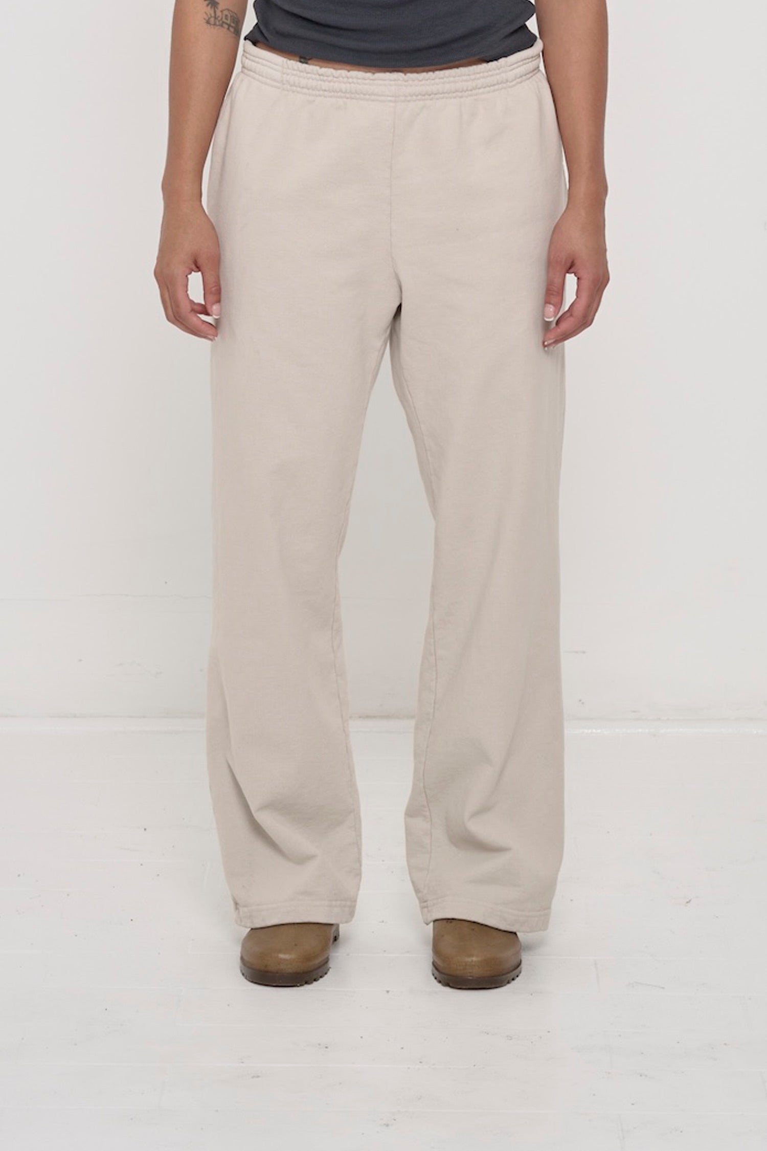 Close-up front view of a person wearing Trash Fleece Apartment Pants in Oat, showing elastic waistband and relaxed drape.
