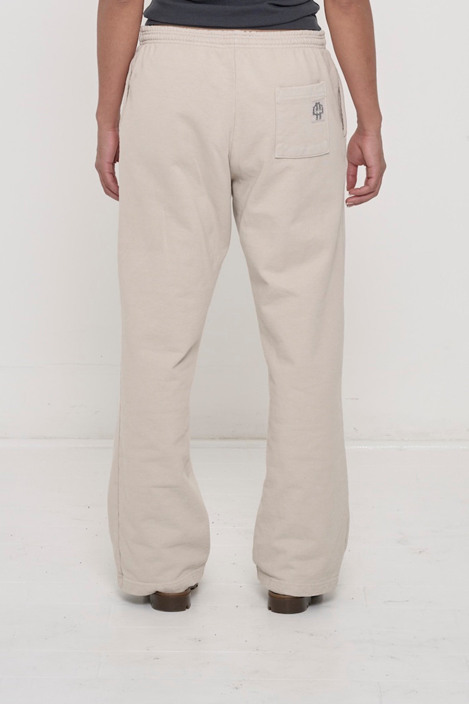Close-up back view of a person wearing Trash Fleece Apartment Pants in Oat, highlighting the back pocket.