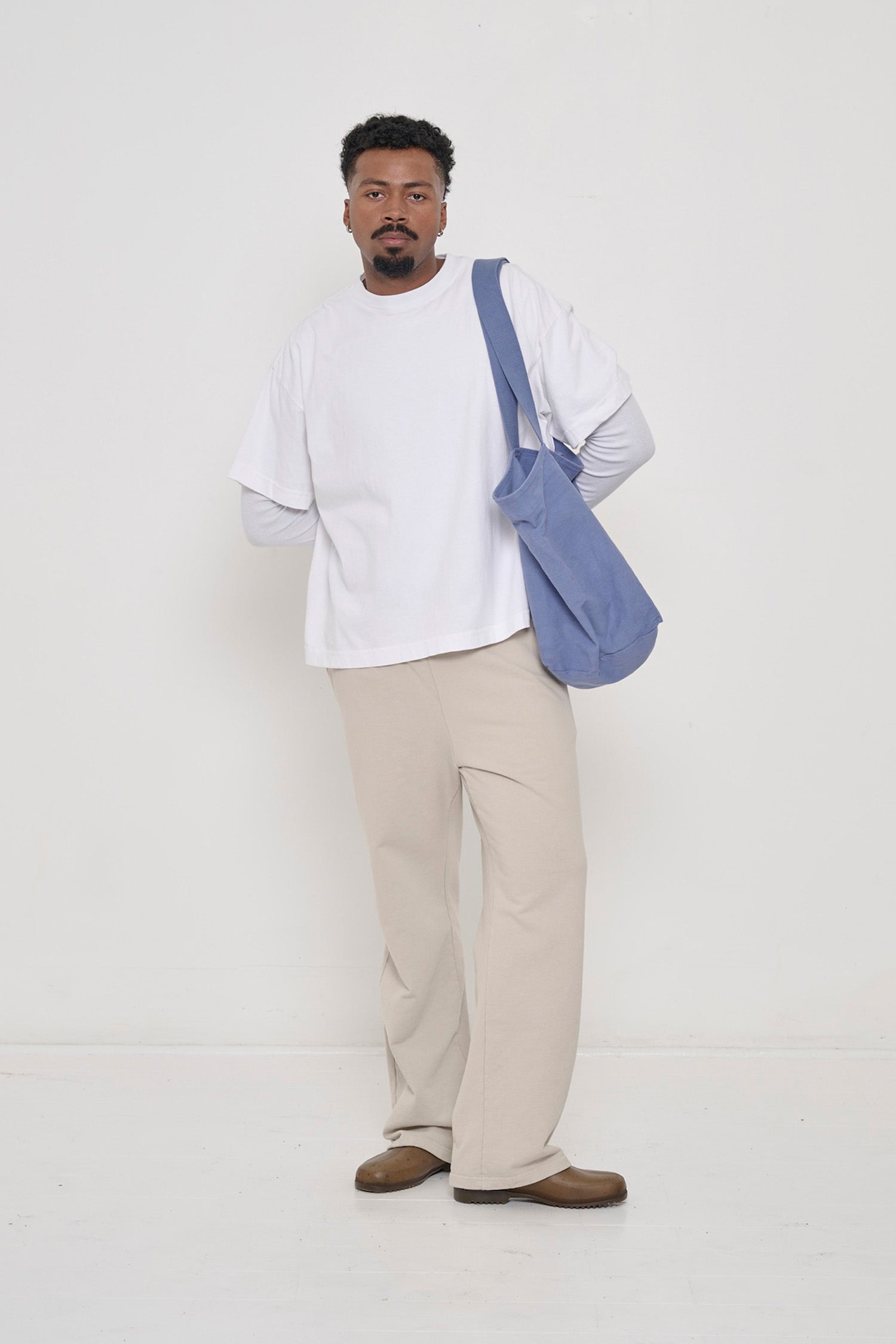A person wearing Trash Fleece Apartment Pants in Oat and Heavyweight Boxier Trash Tee in White.