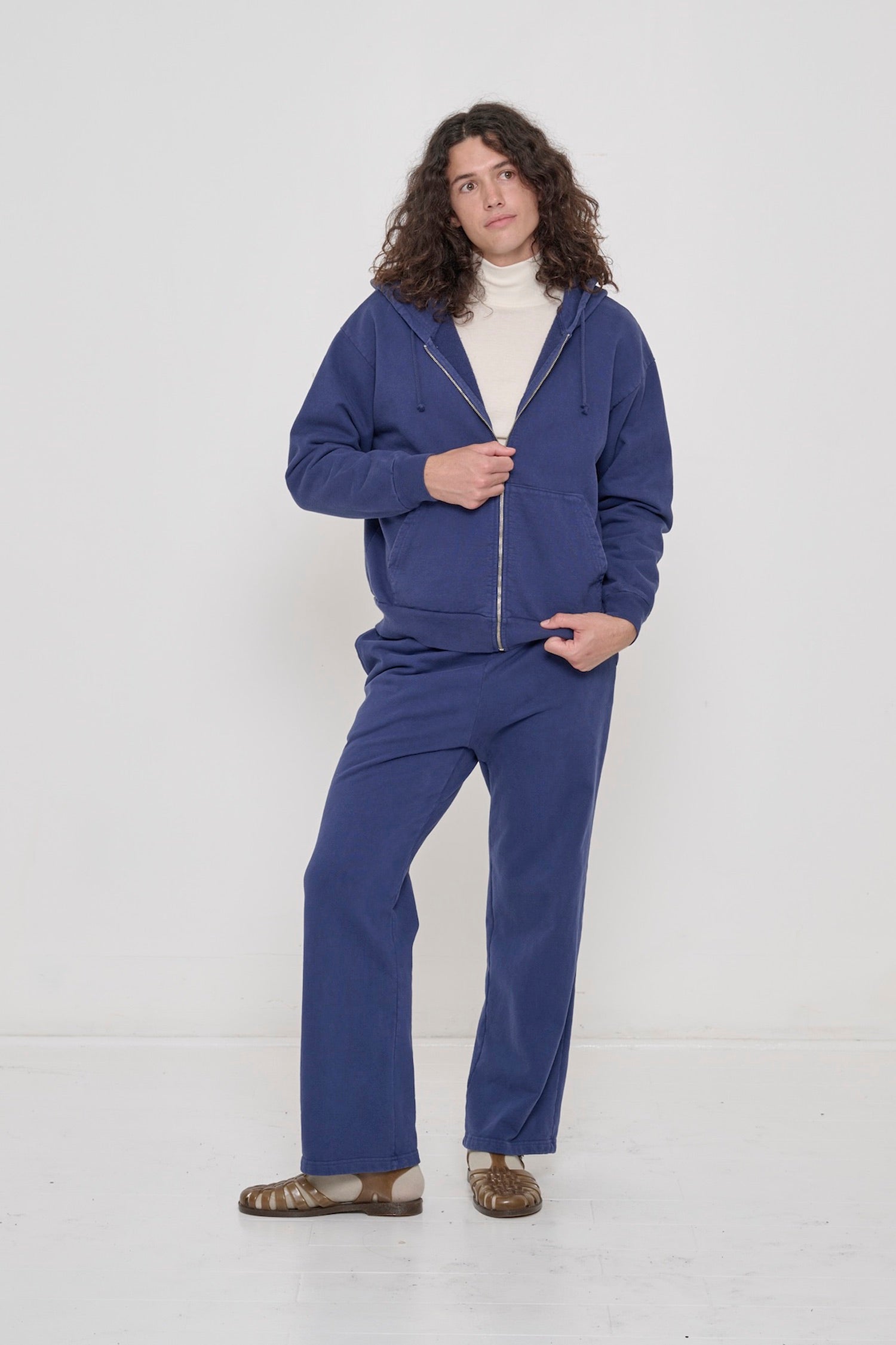A person wearing Trash Fleece Apartment Pants in Washed Navy and Washed Navy Trash Zip Up Hoodie.