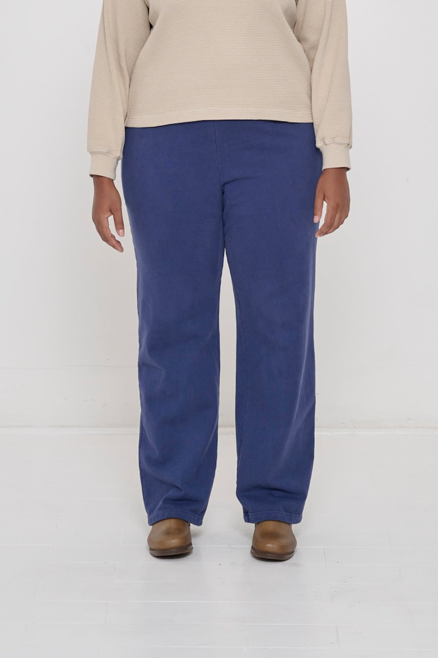 Close-up front view of a person wearing Trash Fleece Apartment Pants in Washed Navy, showing waistband and relaxed drape.