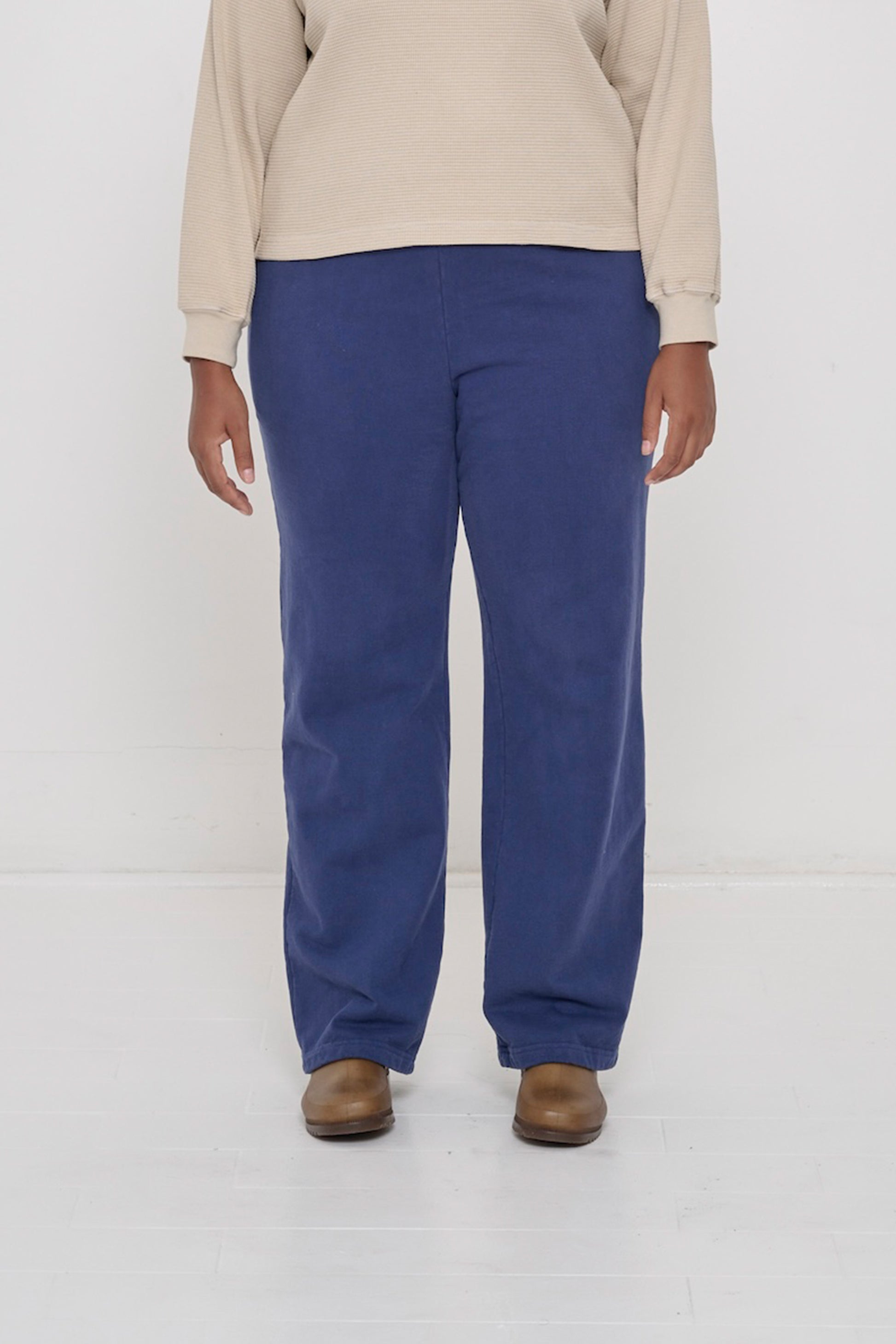 Close-up front view of a person wearing Trash Fleece Apartment Pants in Washed Navy, showing waistband and relaxed drape.