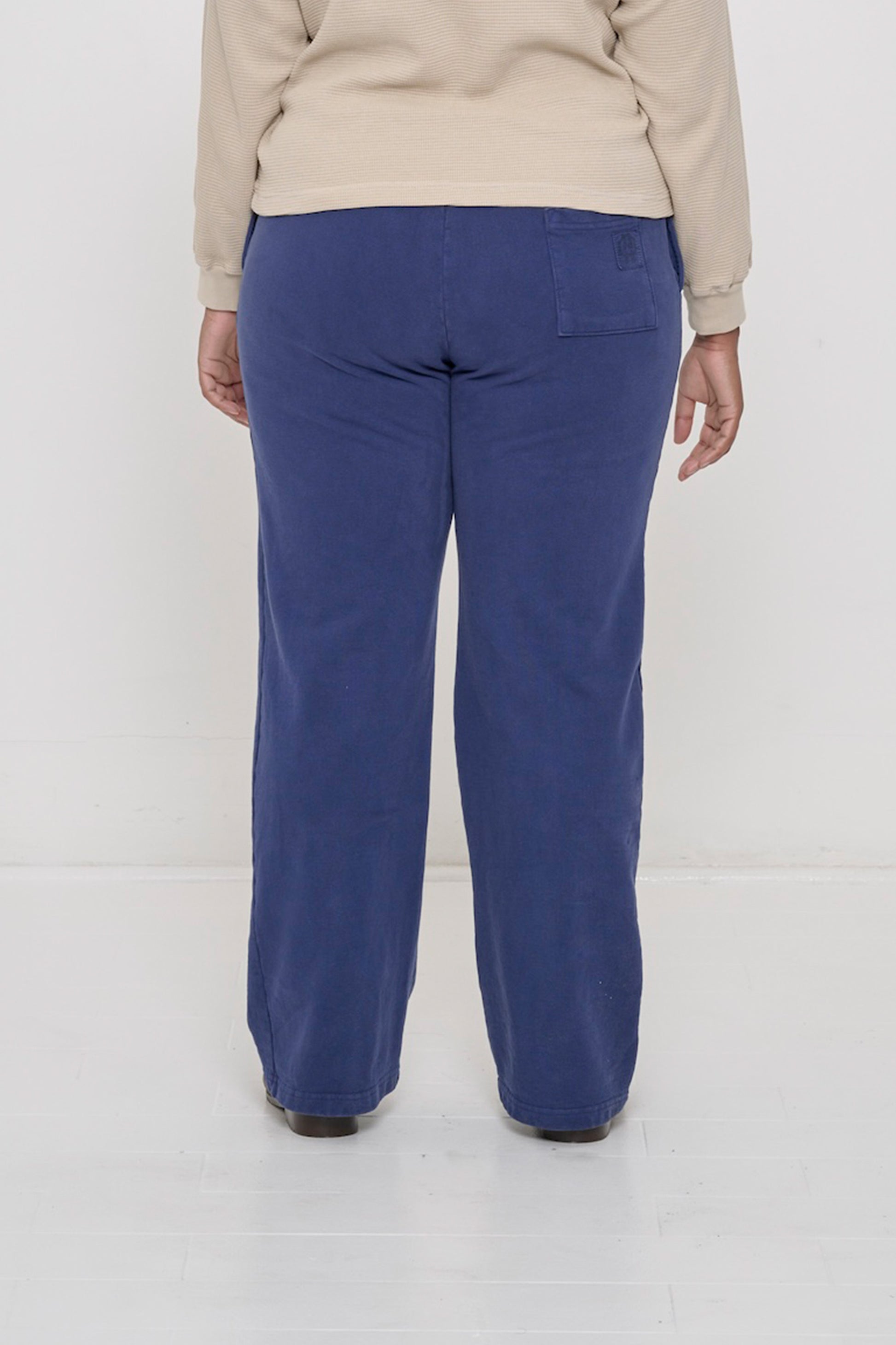 Close-up back view of a person wearing Trash Fleece Apartment Pants in Washed Navy, highlighting the back pocket.